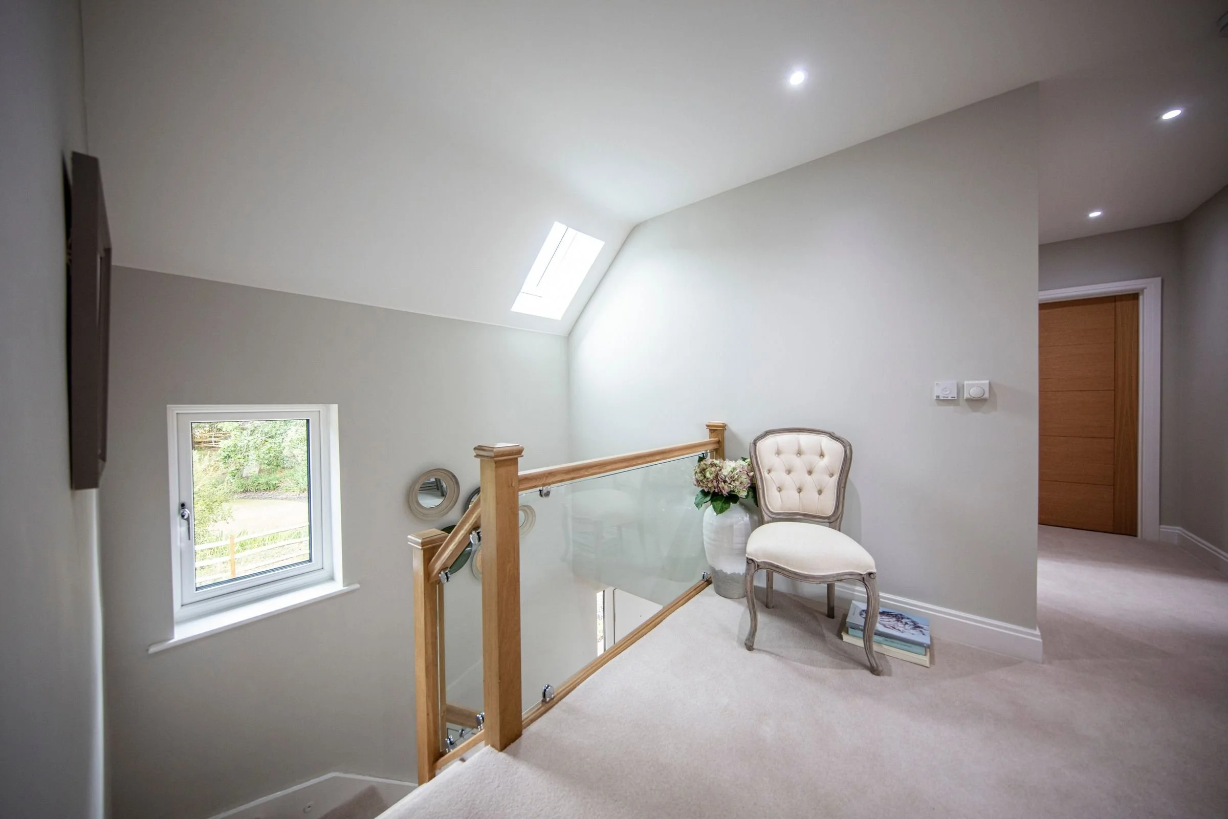First-floor landing with rooflights and a glass balustrade.