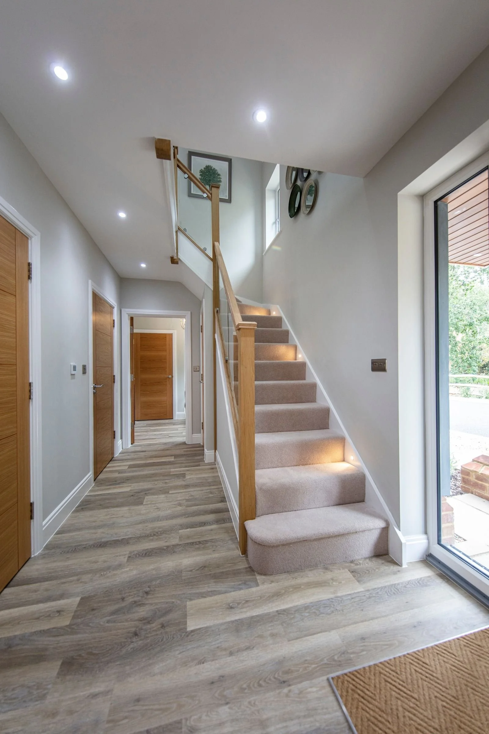 Entrance hall with a glass-balustrade staircase and integrated step lighting.