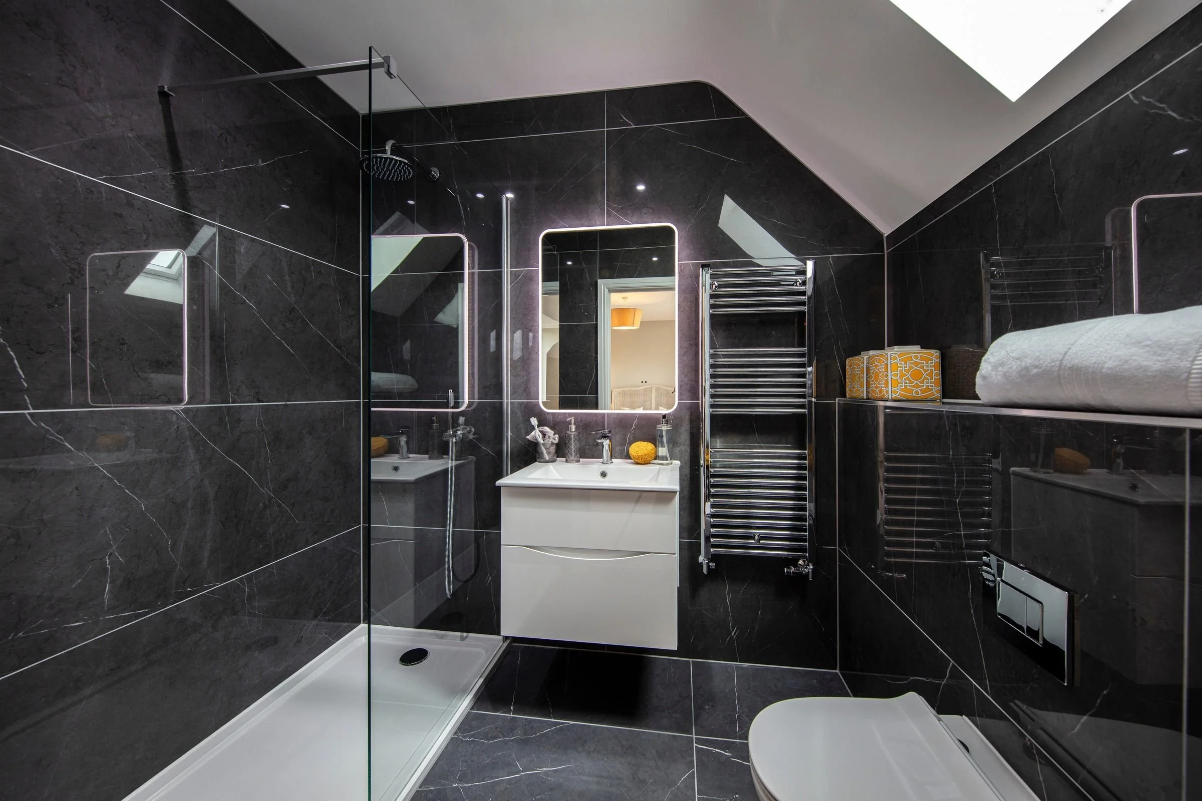 Guest ensuite with a walk-in shower, wall-hung vanity and dark marble-effect tiling