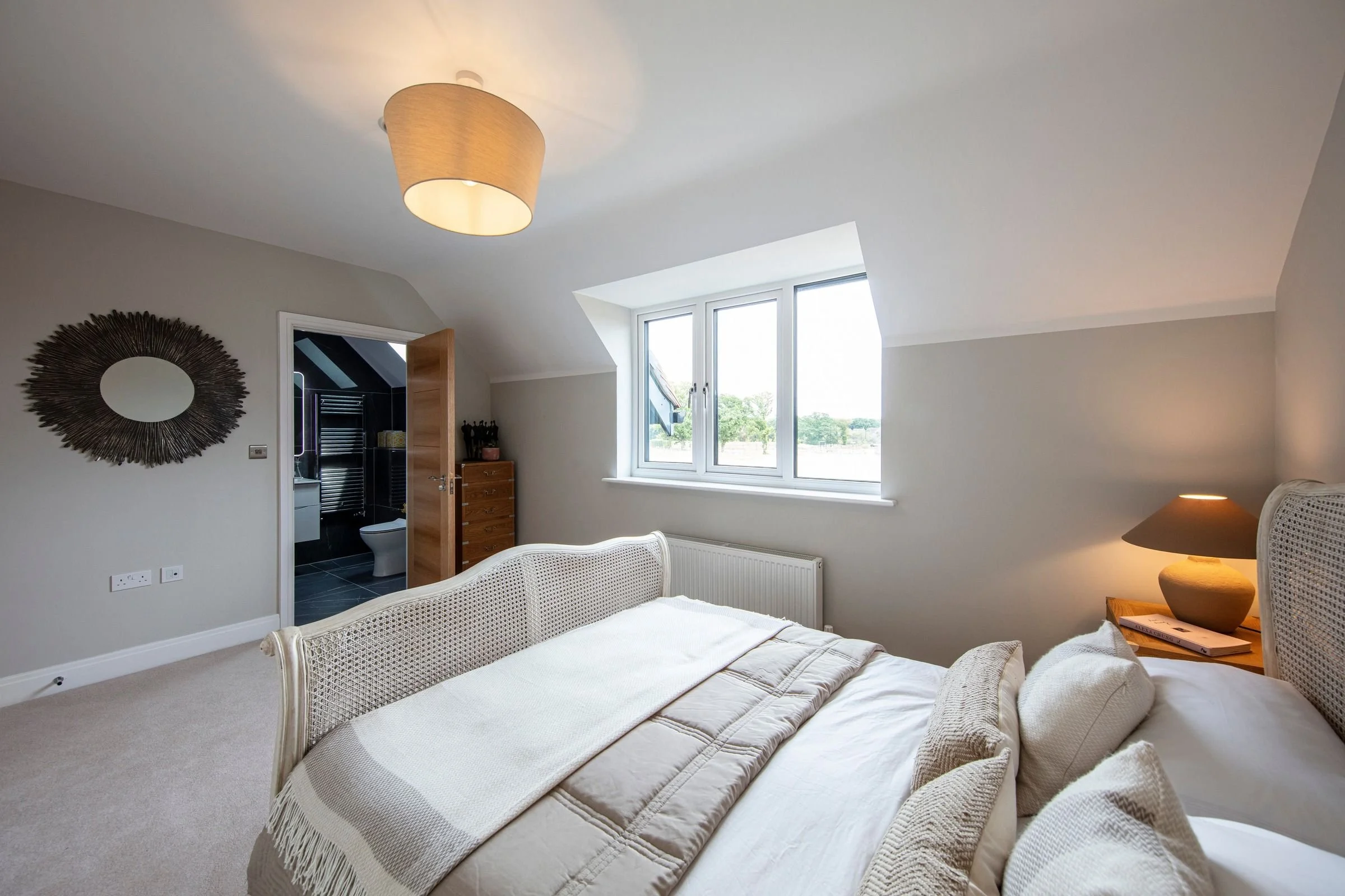 Guest bedroom with a wide window and adjoining ensuite shower room.
