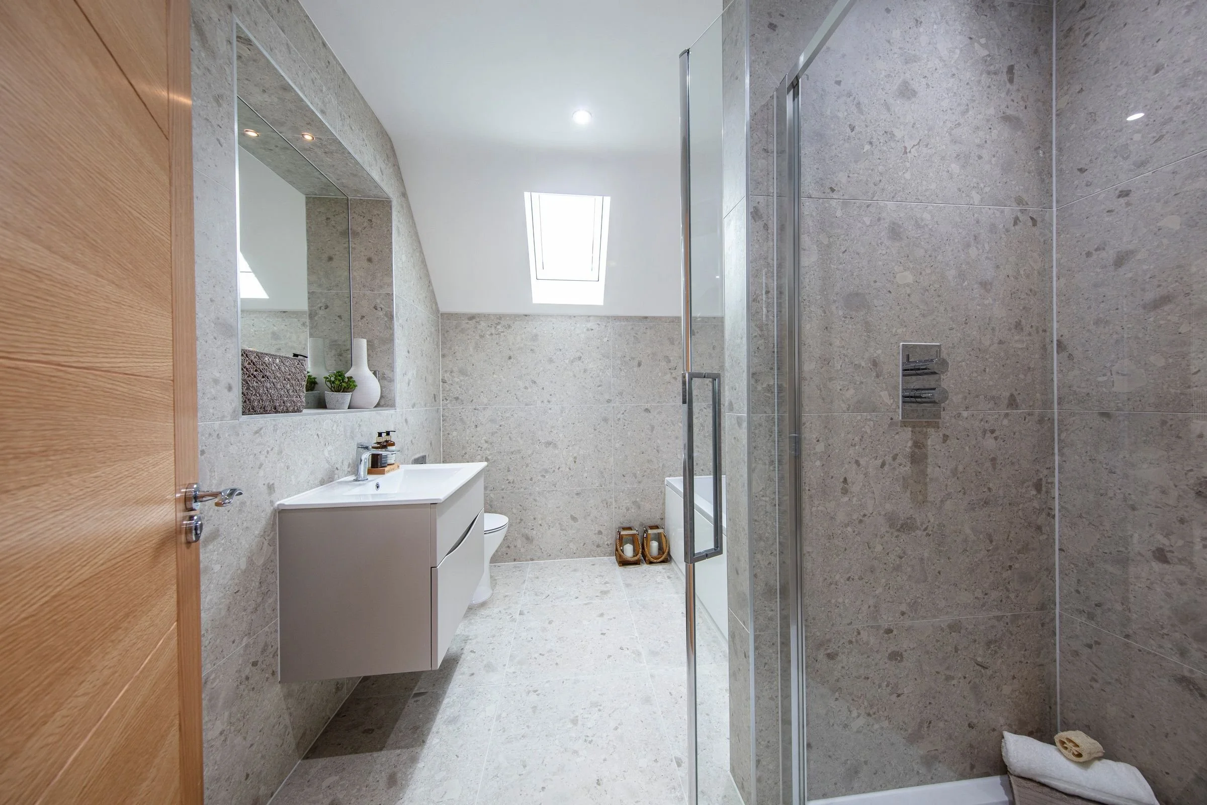 Family bathroom with a separate shower enclosure, wall-hung vanity and marble-effect tiling.