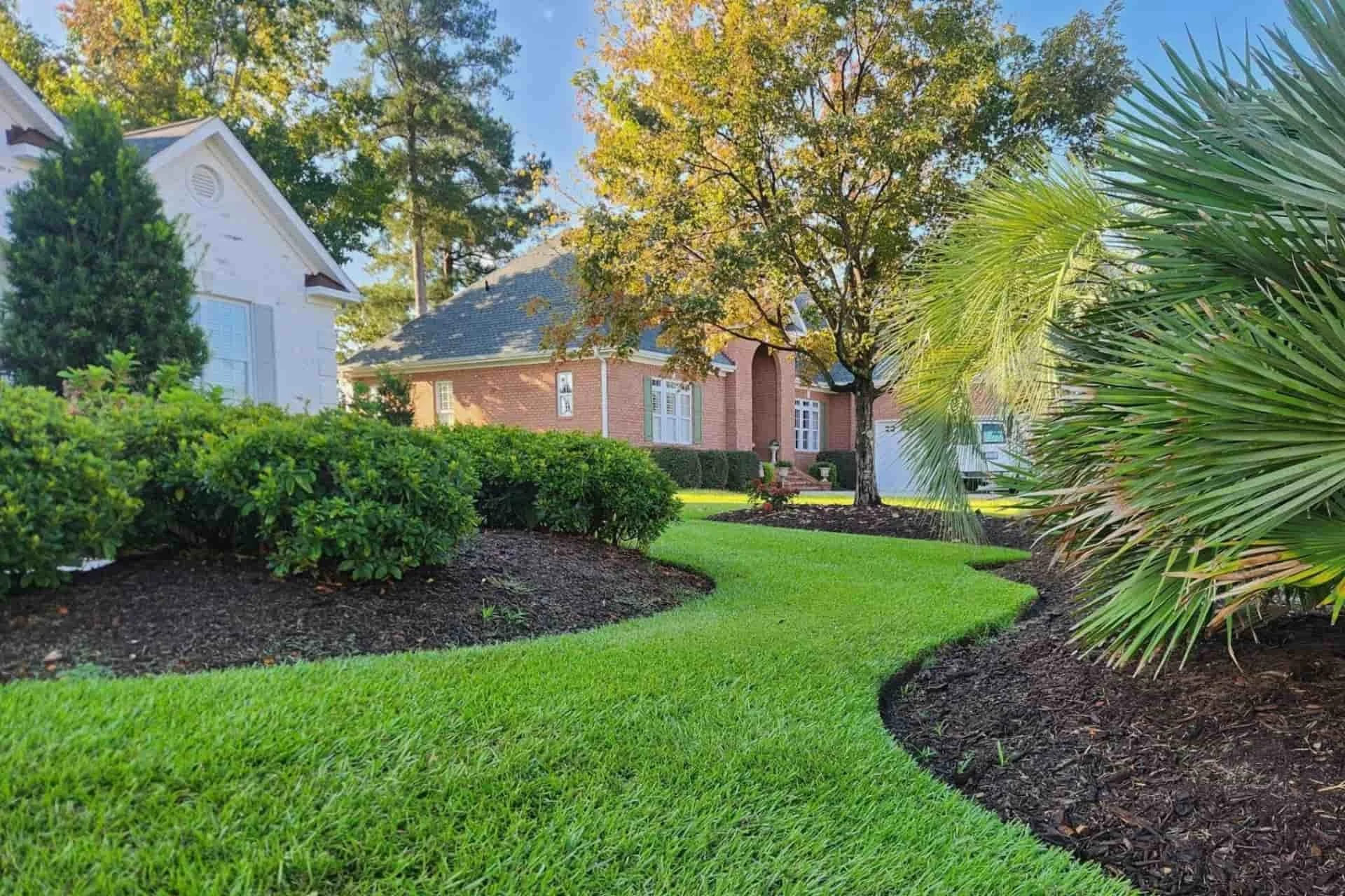 Curved lawn edge with mulched landscape beds and shrubs at a residential property in Wilmington, NC