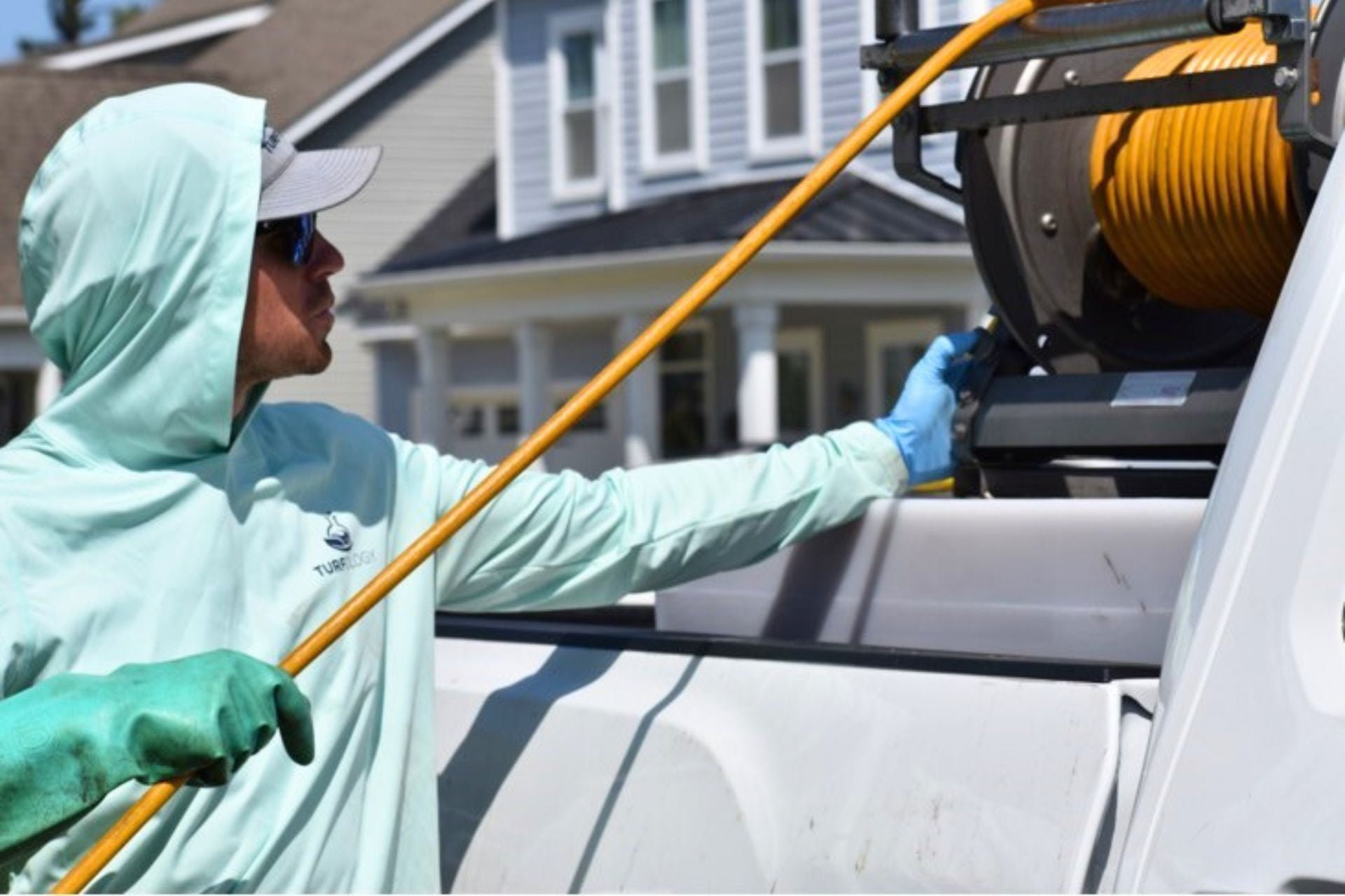 Turfology technician pulling hose from service truck to begin a lawn treatment application in Wilmington, NC
