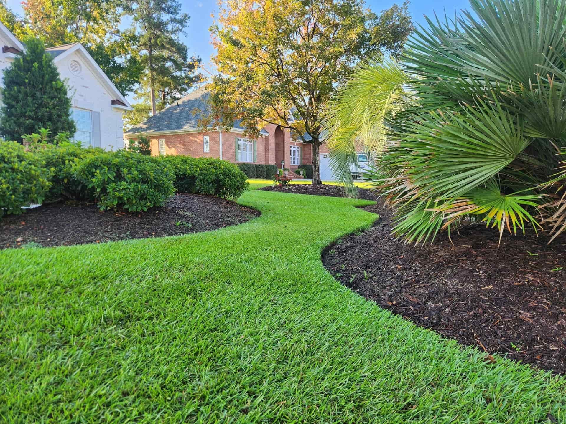 Green residential lawn with shrubs and trees with houses in the background