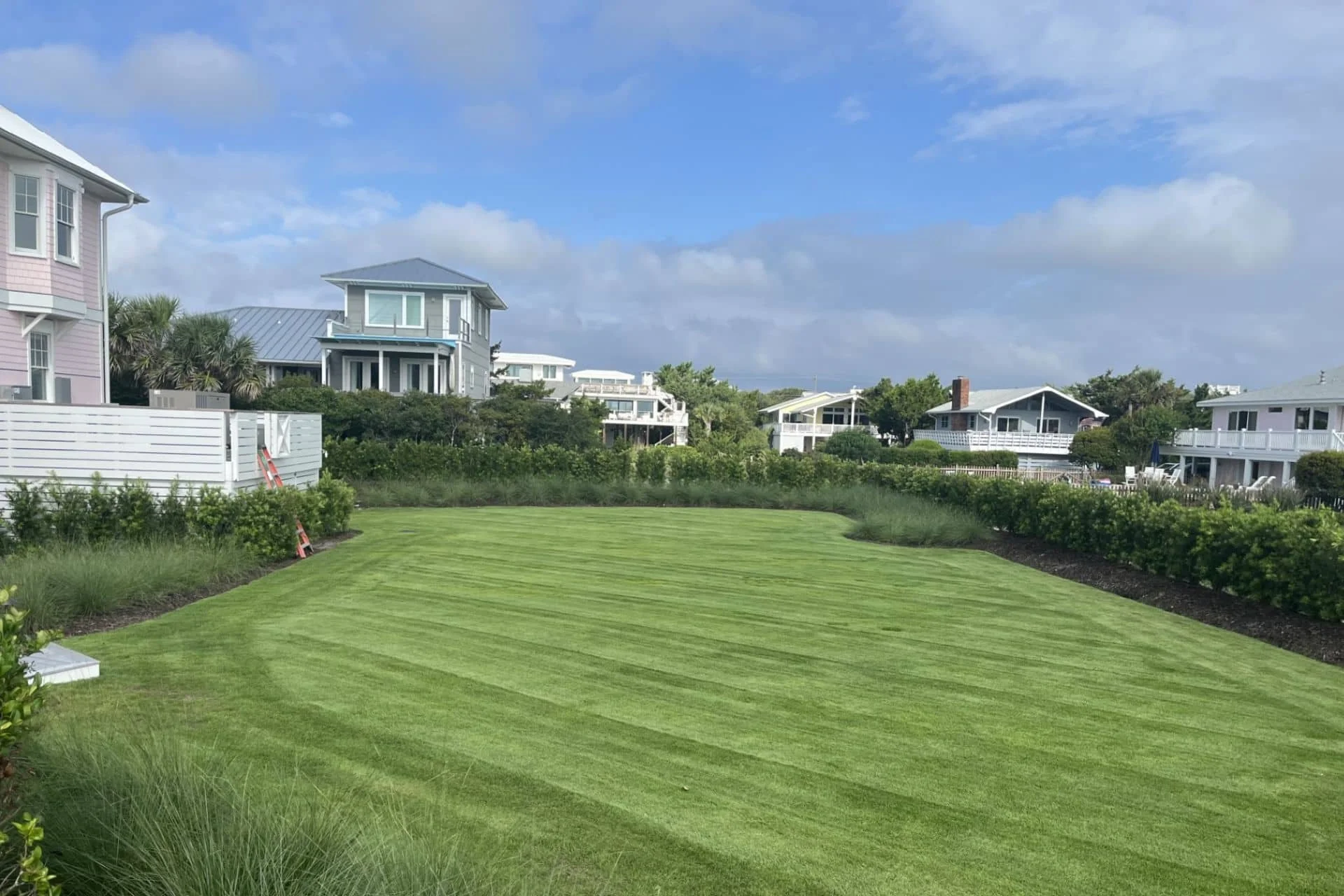 Freshly striped coastal lawn with ocean-view homes in the background near Wrightsville Beach, NC