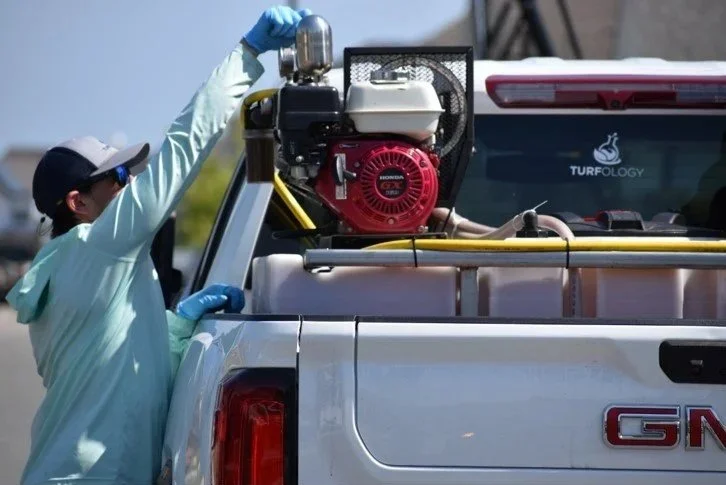 Turfology technician loading equipment onto a service truck before a lawn treatment in Wilmington, NC