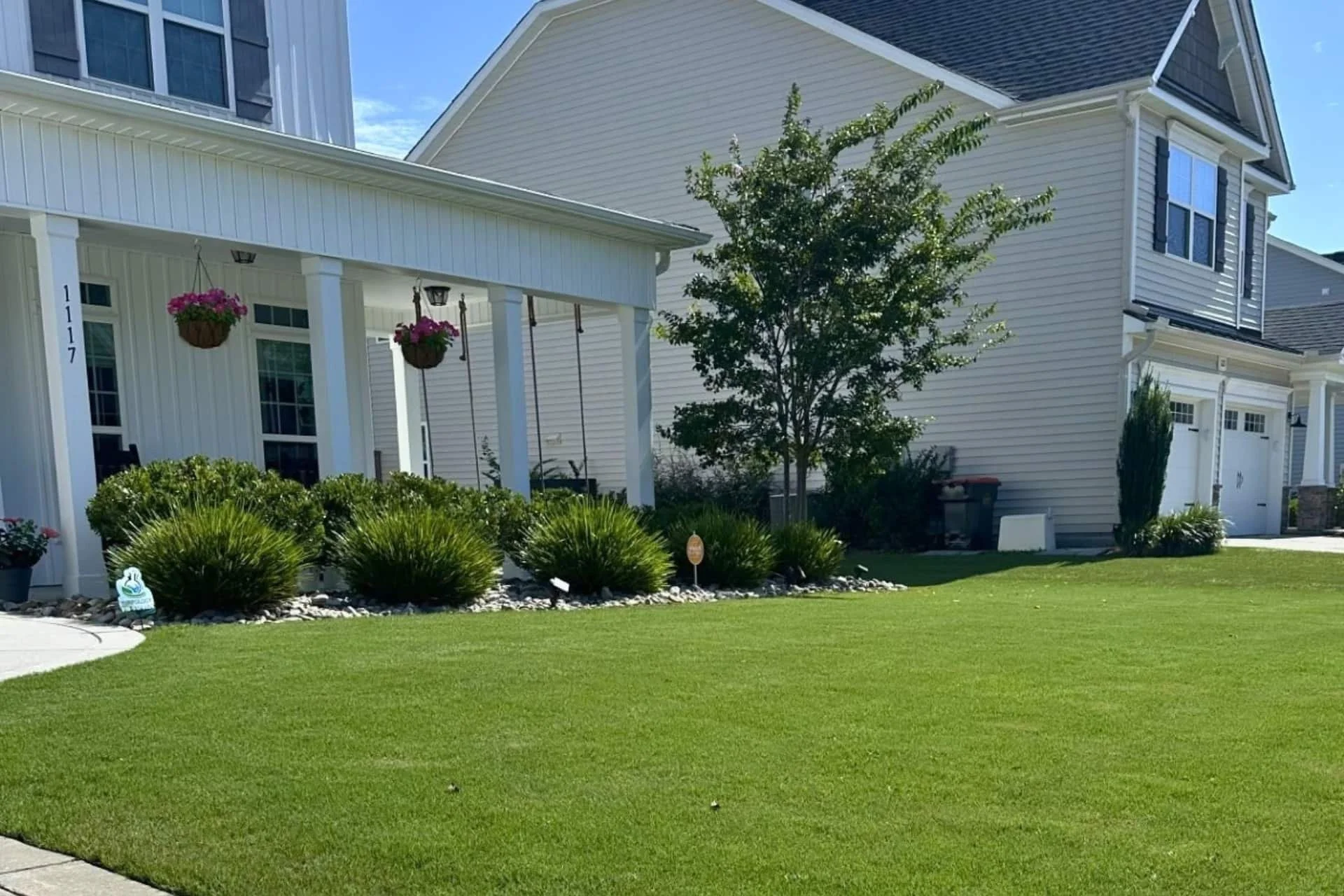 Freshly mowed front lawn with hanging porch plants and landscaped beds at a residential home in Wilmington, NC