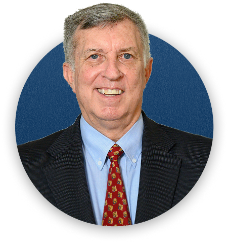 Portrait of a middle-aged man in a business suit with a blue background.