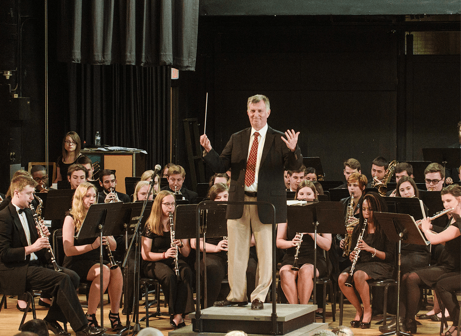 Orchestra performing on stage with conductor leading the group.