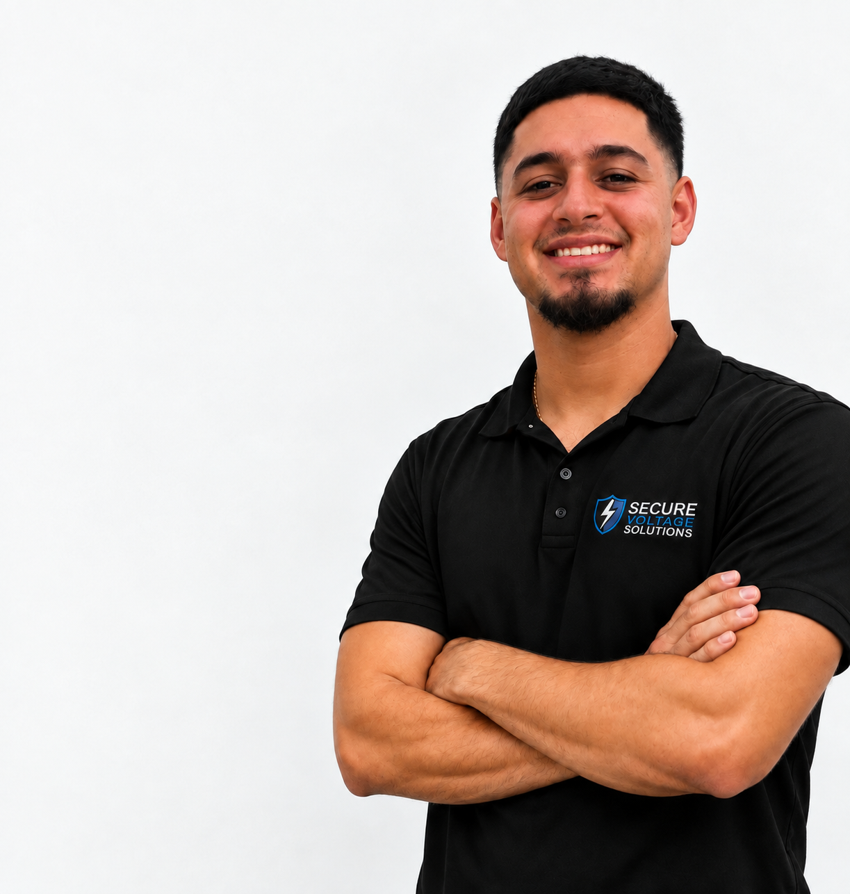 A smiling man with dark hair and a beard, wearing a black polo shirt with a logo that says 'Secure Voltage Solutions,' standing against a plain white background with arms crossed.
