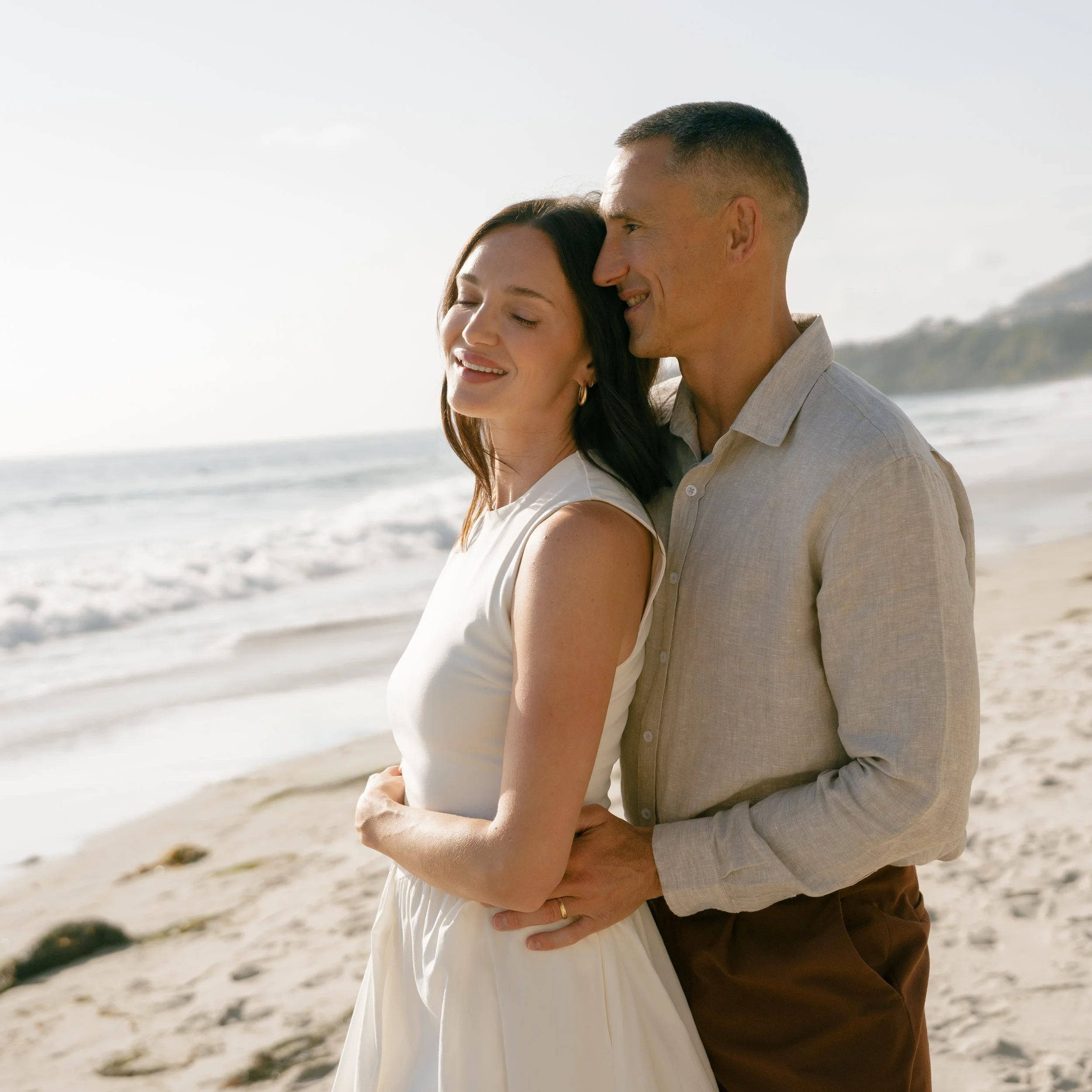 Julia and Rob Hoadley embracing on the beach for a couples lifestyle photoshoot in Southern California. 