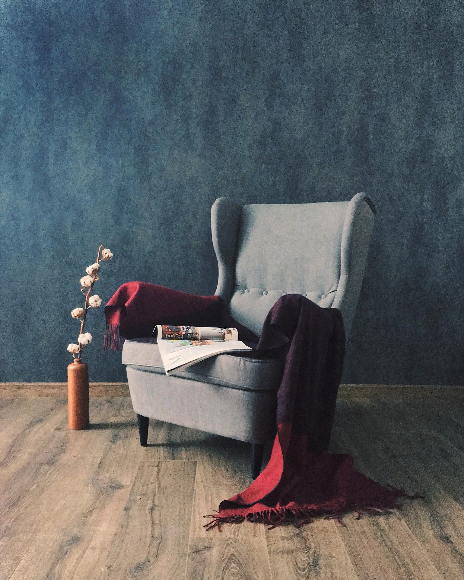 Cozy chair with blanket, single flower, and magazine. A warm, welcoming space at Sheri's Place