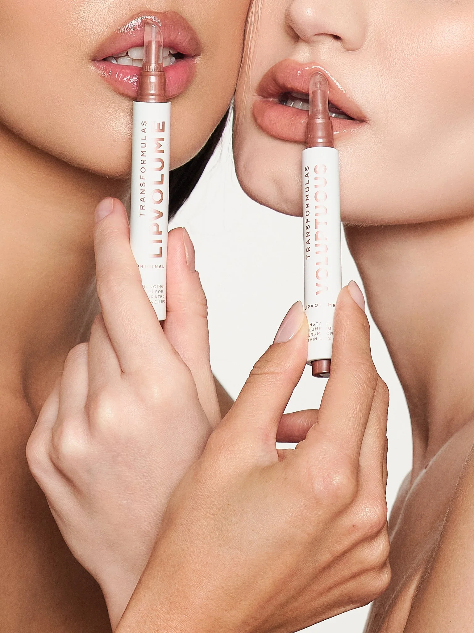 Two women are holding lip gloss tubes near their lips, showcasing the lip gloss product.
