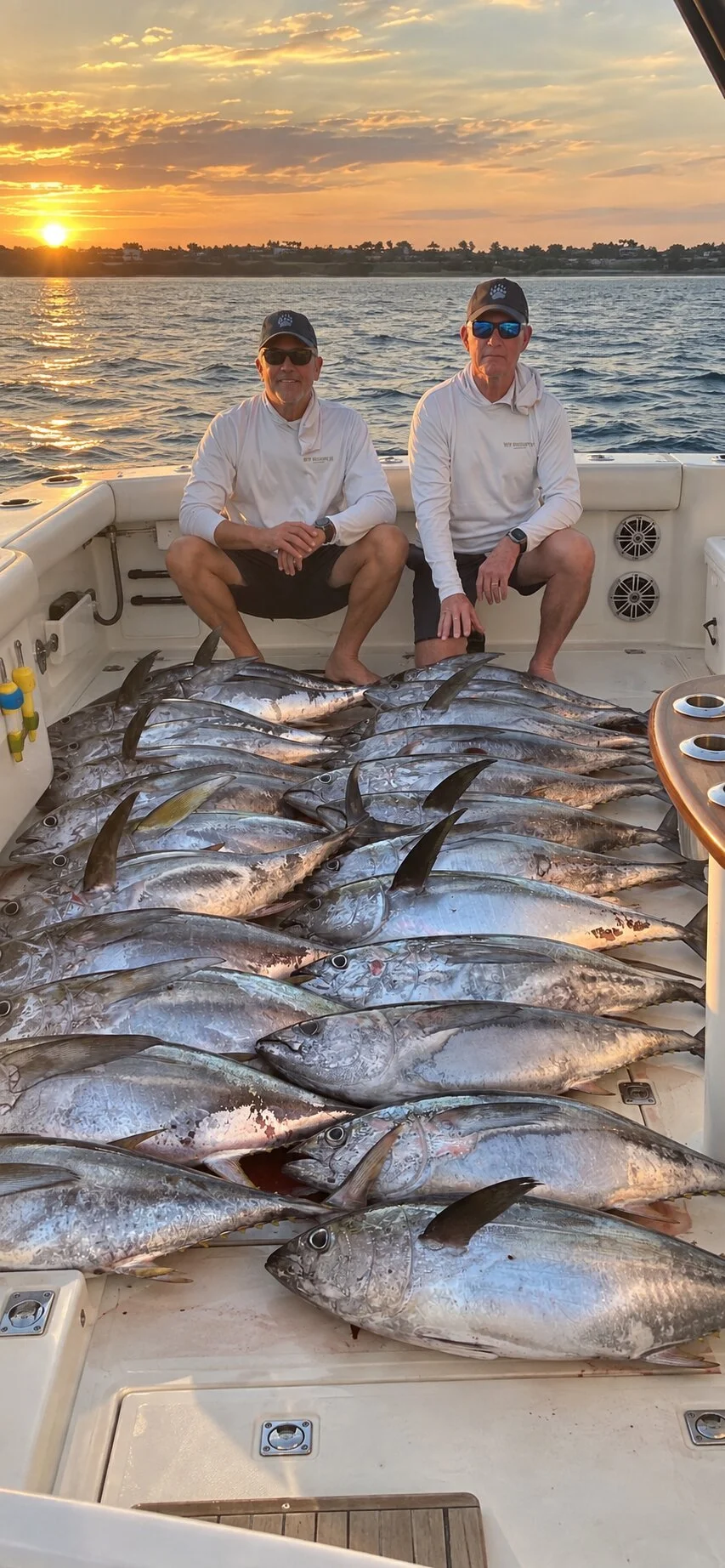 Two anglers at sunset behind a deck of tuna