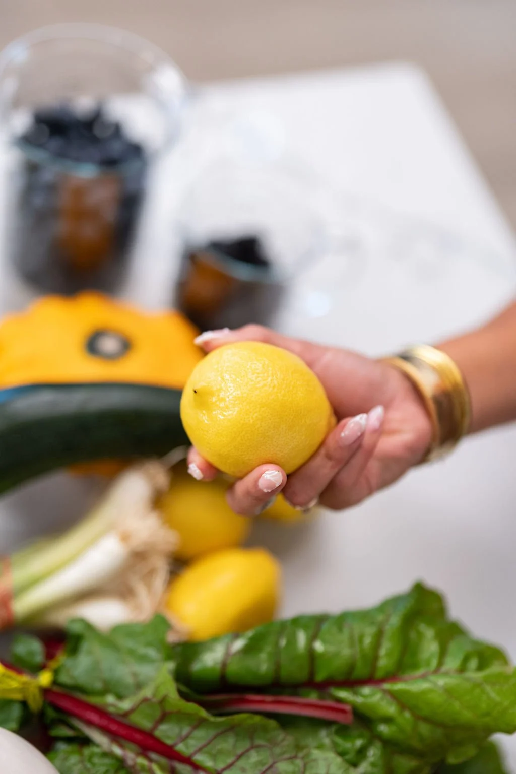Liv holding a bright yellow lemon with other vegetables in the background