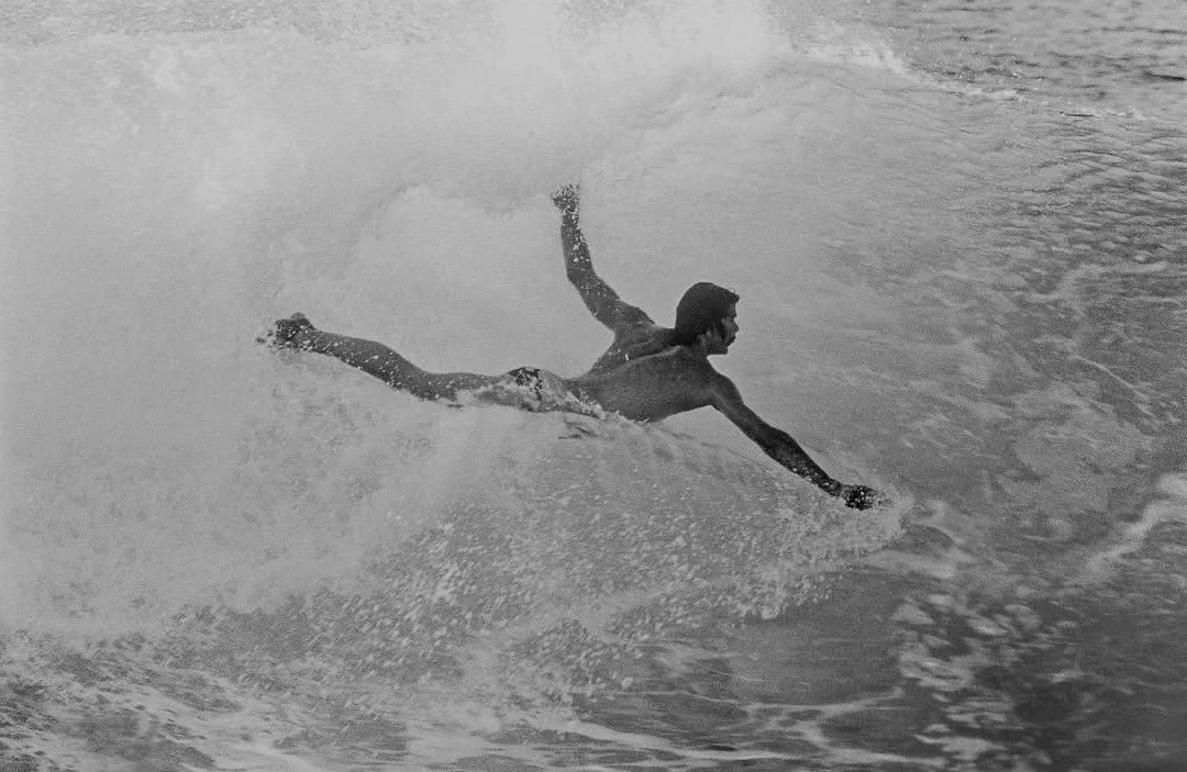A classic photography of a person surfing on a wave in the ocean. Bumi Adventures.
