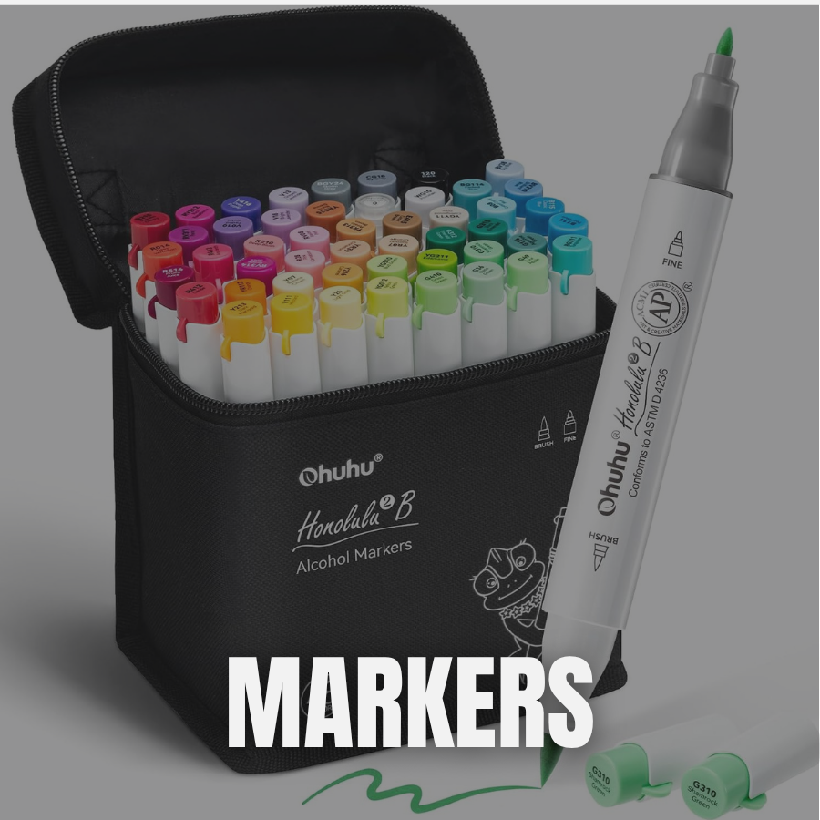 A black case filled with alcohol markers in various colors, with some colors labeled on the caps, and a large white marker outside the case. The case and markers are on a gray surface, with a green ink mark and green caps visible.