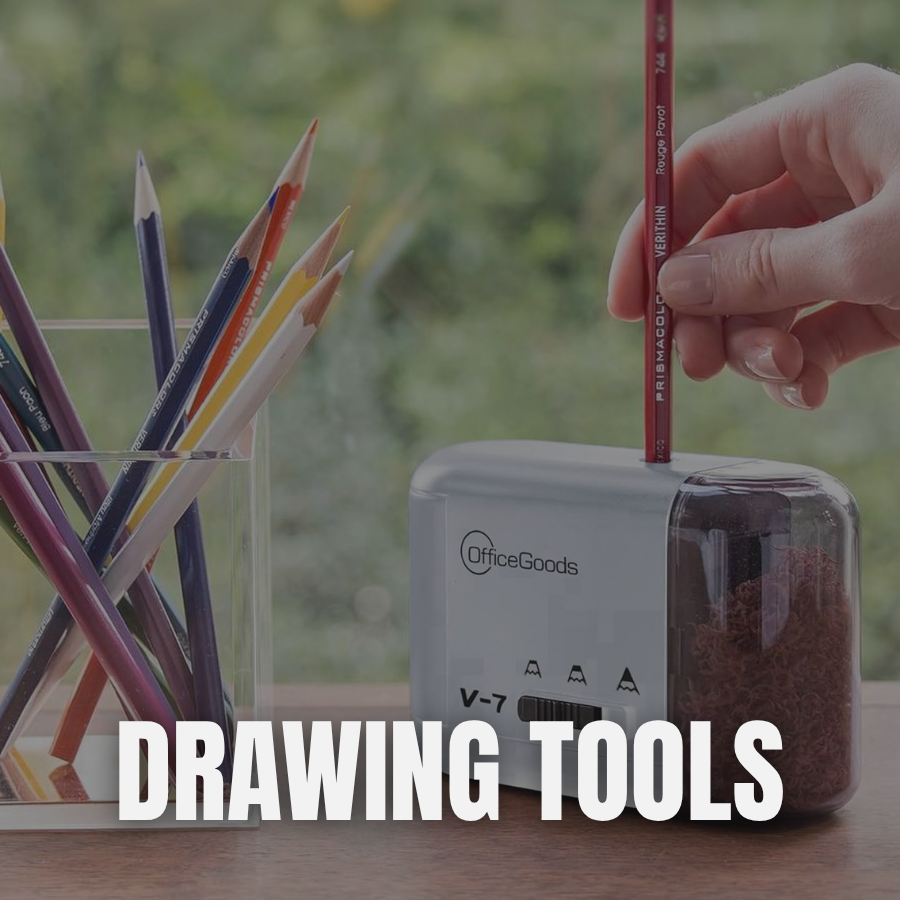 A hand using a red colored pencil with a PVC eraser to insert into a white OfficeGoods pencil sharpener, with a container of colored pencils nearby on a wooden surface and a blurred window background.