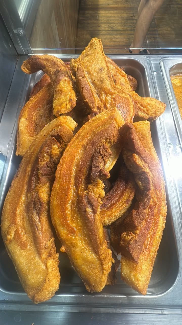 Several pieces of fried pork belly with crispy skin displayed in a stainless steel tray.