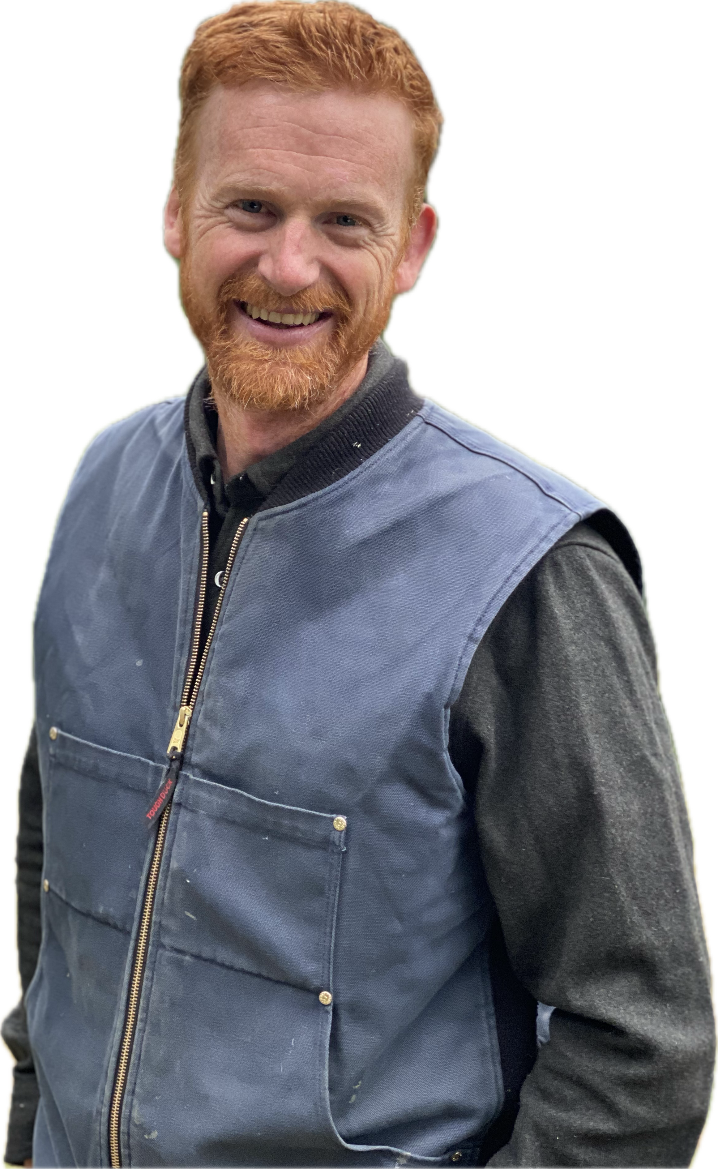 A smiling man with red hair and a beard, wearing a blue jacket over a long-sleeve shirt.