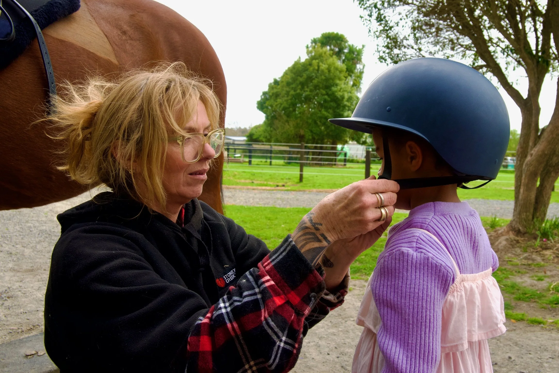 human equined assisted learning - safety first, founder of heal places helmet on students head.