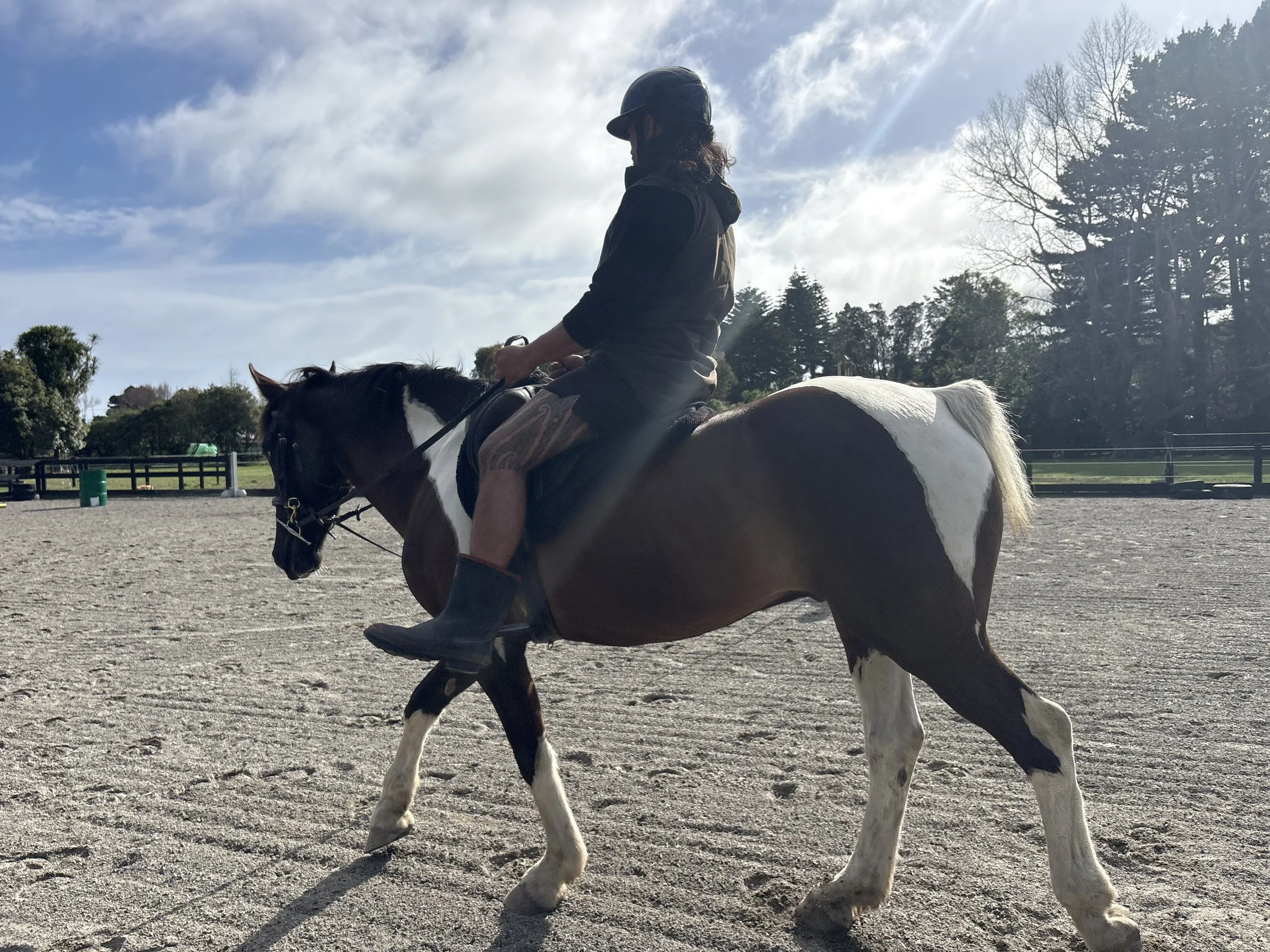Human equine assisted learning student having a riding lesson after breaking his back riding - older maori man.