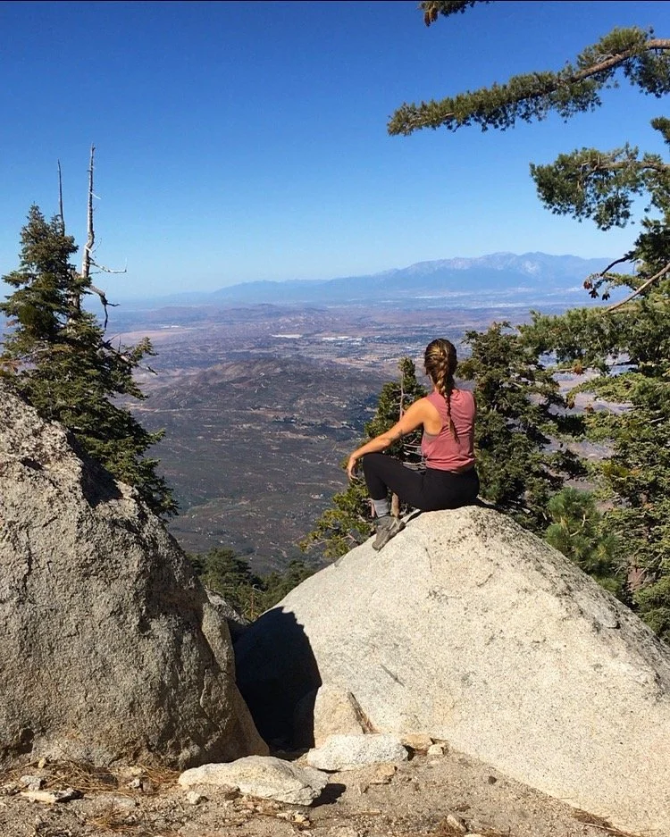 Hiker sitting on a granite boulder overlooking a mountain valley