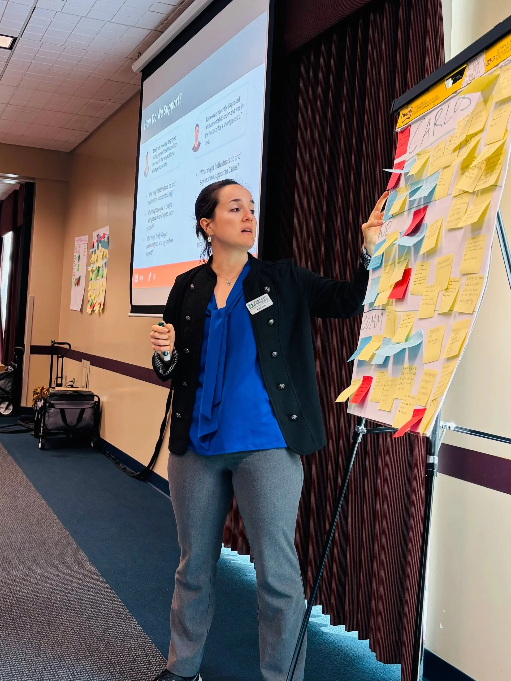 Woman teaching a class with chart paper, sticky notes, and a PowerPoint presentation