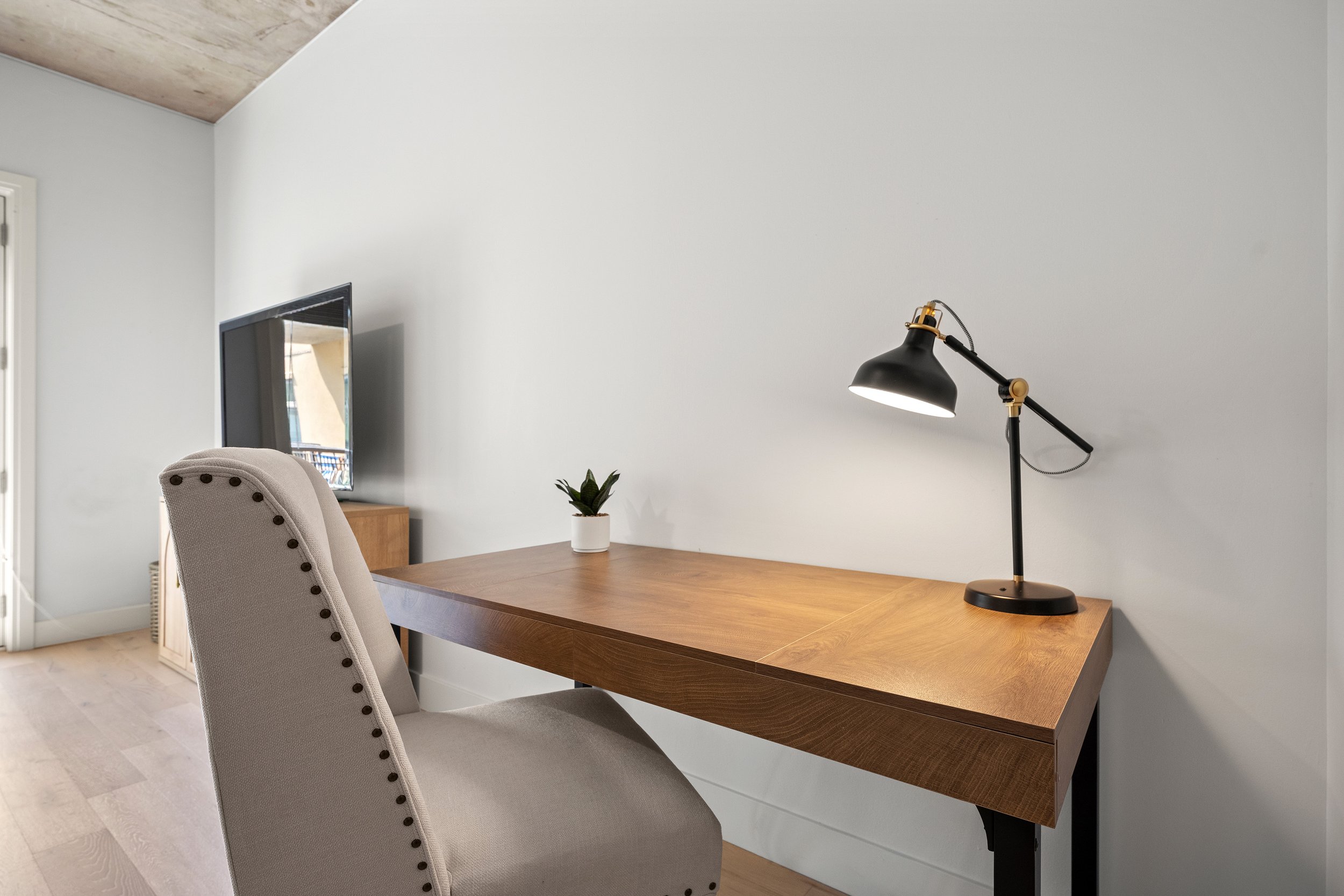 In home office desk with wood work surface, shelving, and task lighting.