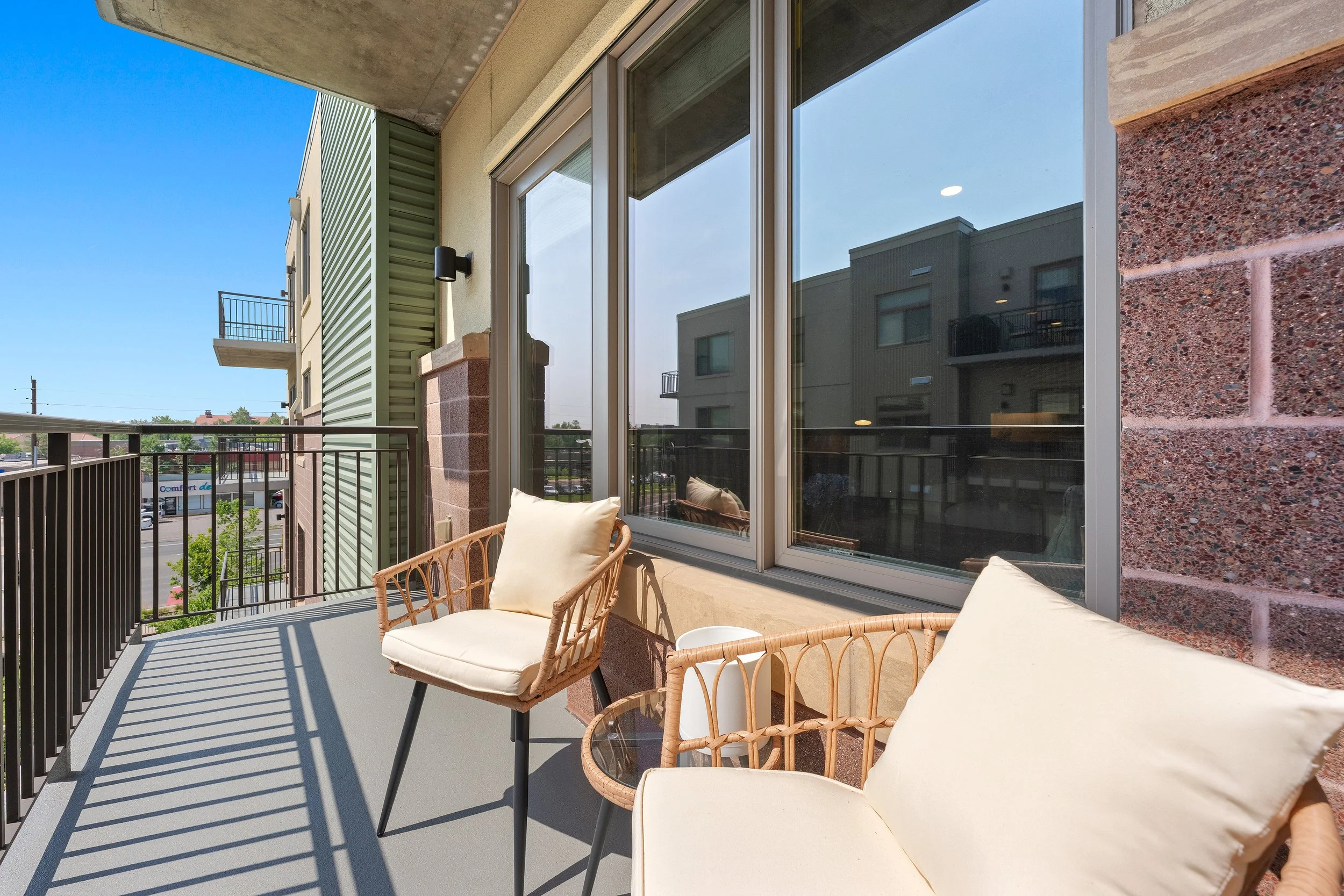 Covered balcony with outdoor seating, large windows, and views of the surrounding neighborhood.