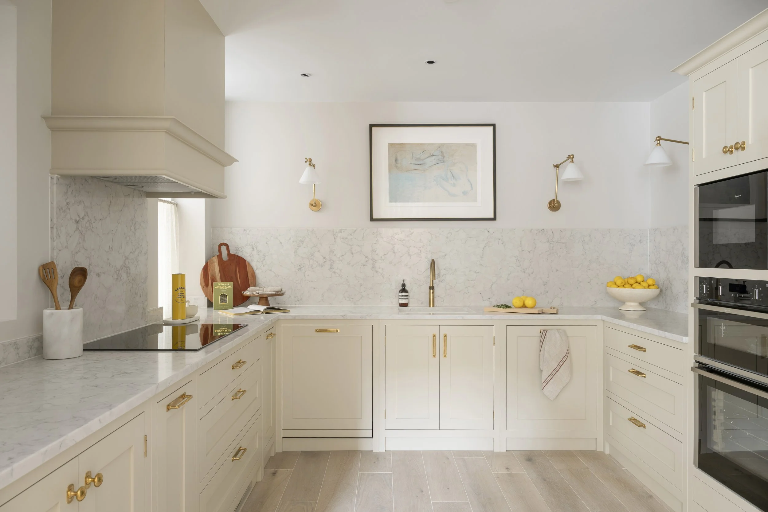 Grove modern kitchen with beskoke cabinetry and marble countertops. The kitchen has brass hardware, wall-mounted white and brass lamps.