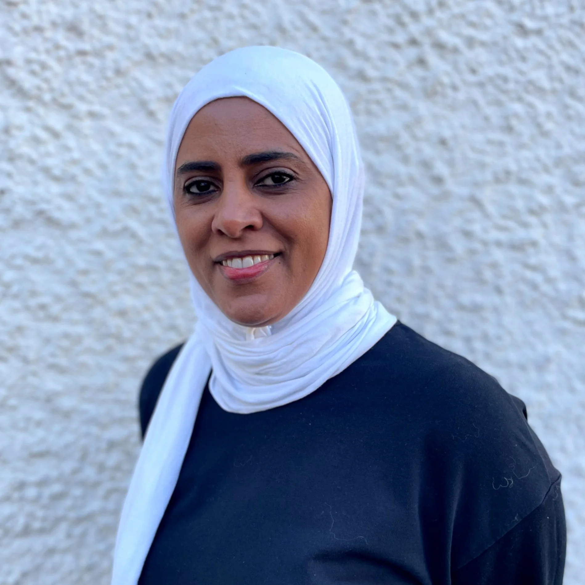 Vänsterhalv face av en kvinna med hijab som ler.