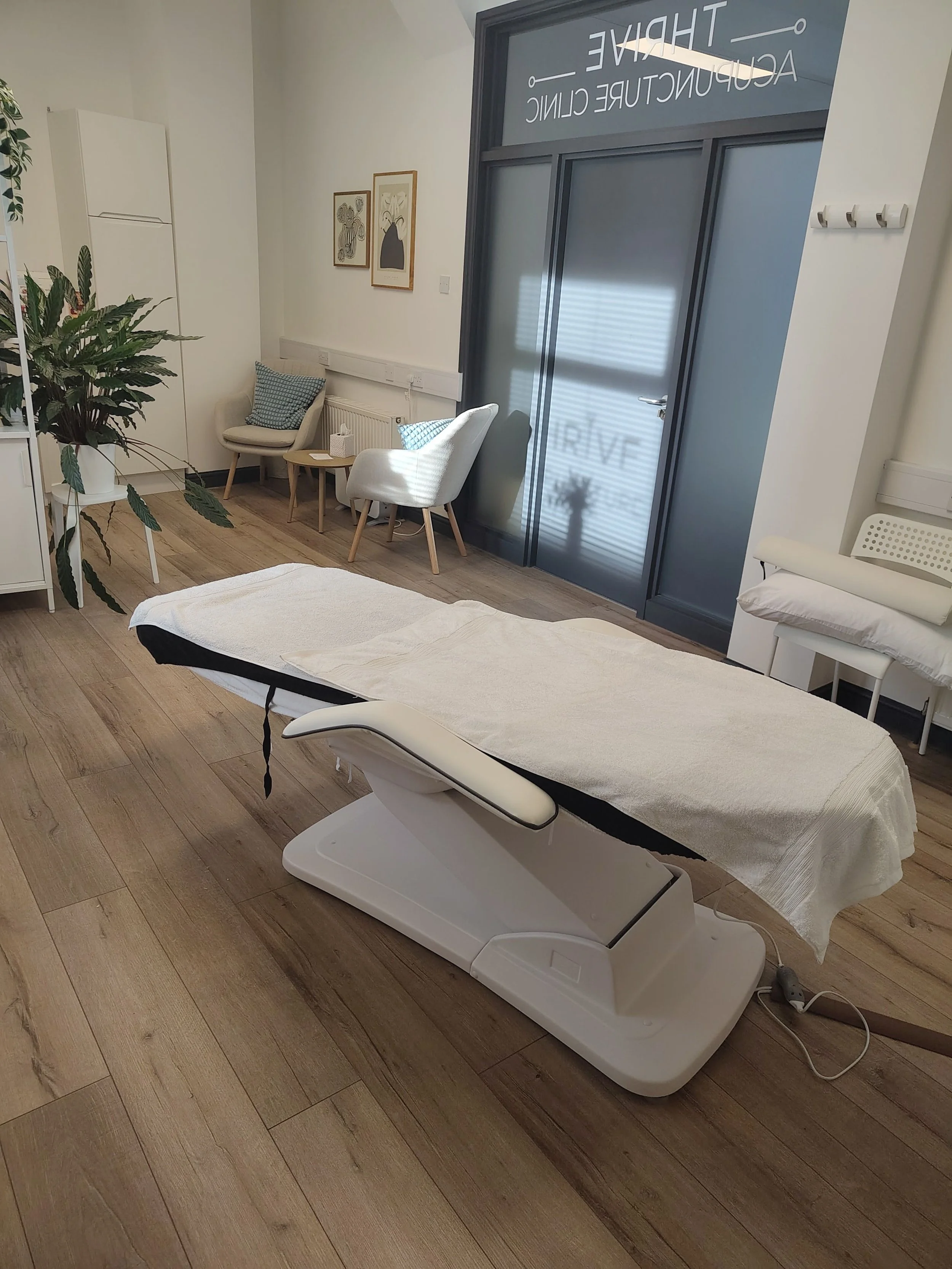 A sports massage bed covered with a white sheet in a room with wooden flooring, with a large ultrasound machine beside it. Sports Massage available in Otley in evenings and Weekends