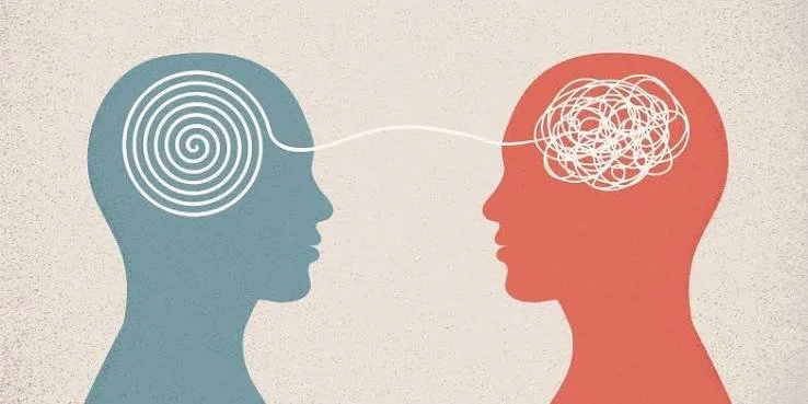 Illustration of two human heads facing each other, one with a spiral in the brain area and the other with a tangled scribble, connected by a line suggesting communication or thought exchange.