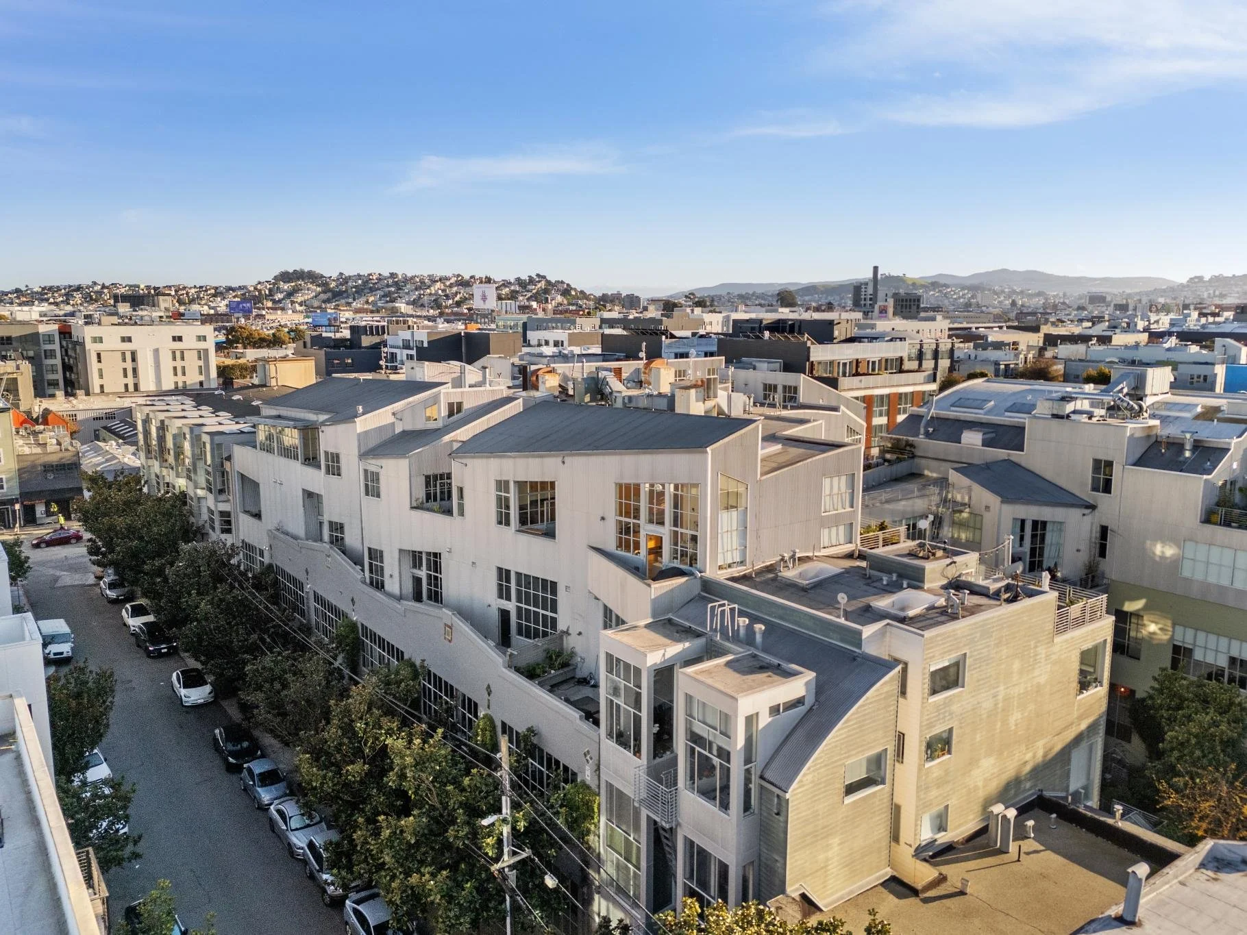 High-angle view of a cityscape with modern residential buildings and a hilly background under a clear blue sky.