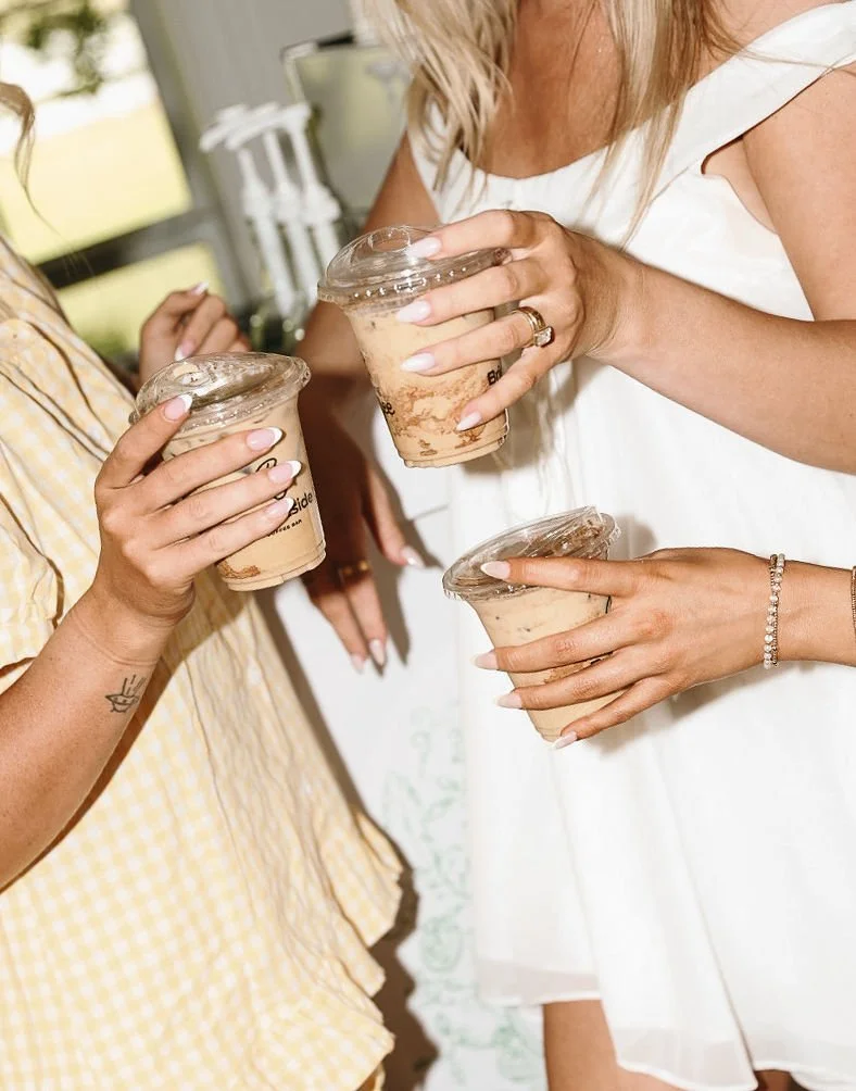 Two bridesmaids holding cups of coffee with whipped cream in Ro Manor's getting ready house.