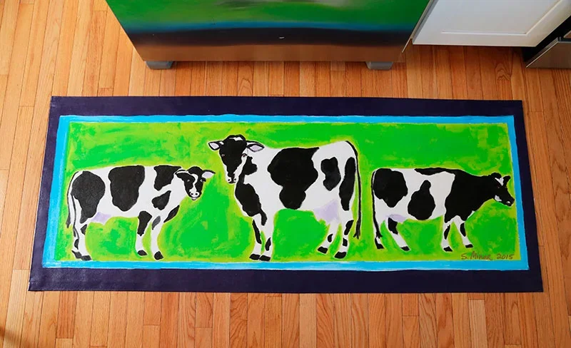 Kitchen with hand-painted canvas runner of black and white cows on green background
