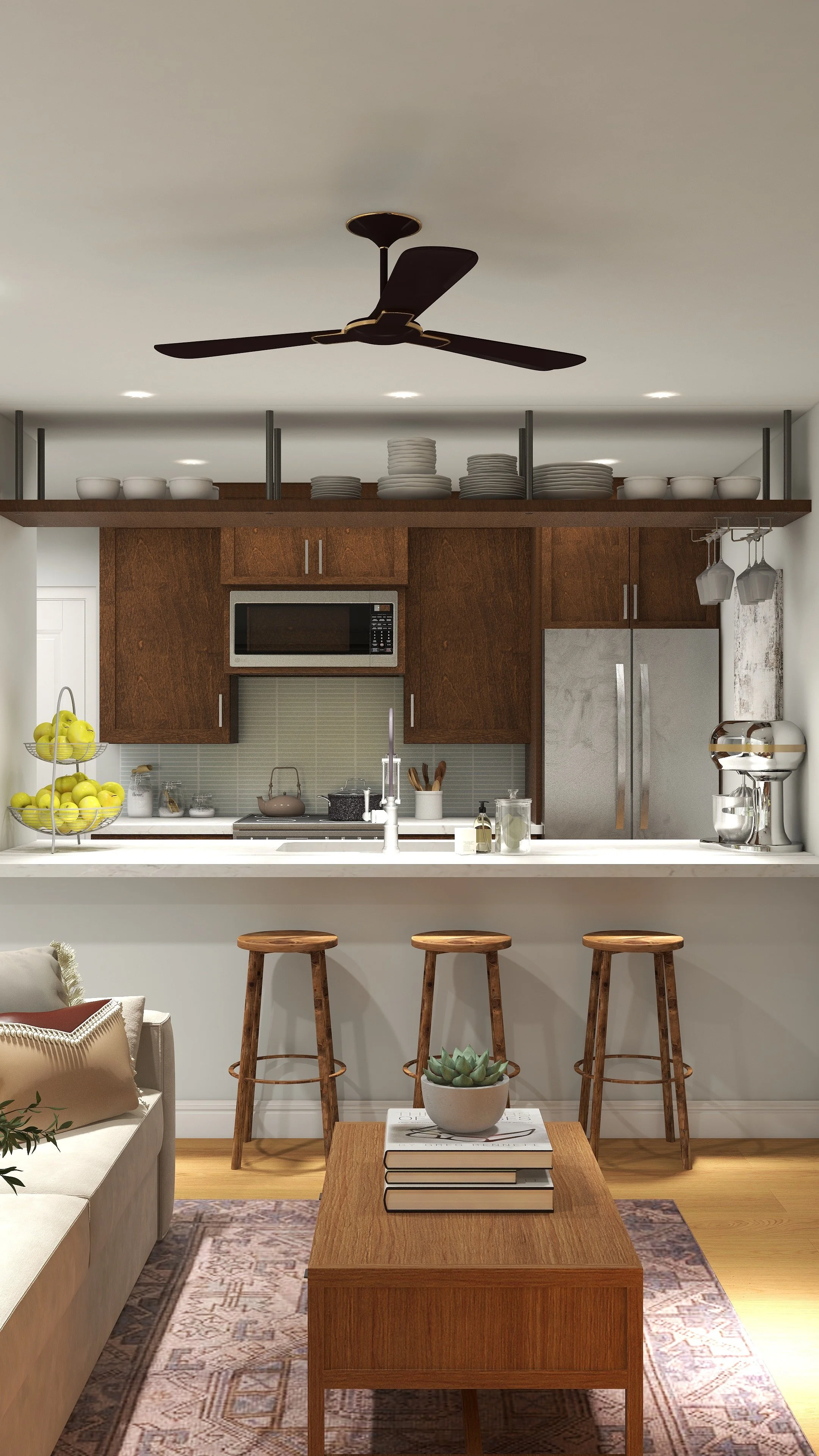 A modern kitchen with wooden cabinets, a microwave, a refrigerator, and a white countertop. There is a three-tier fruit stand with green apples, a tea kettle, and various kitchen utensils. Overhead, there is a wooden shelf with neatly stacked plates and bowls. Three barstools are positioned in front of the counter, and a living area with a beige sofa, a wooden coffee table with books and a succulent plant, and a patterned rug.