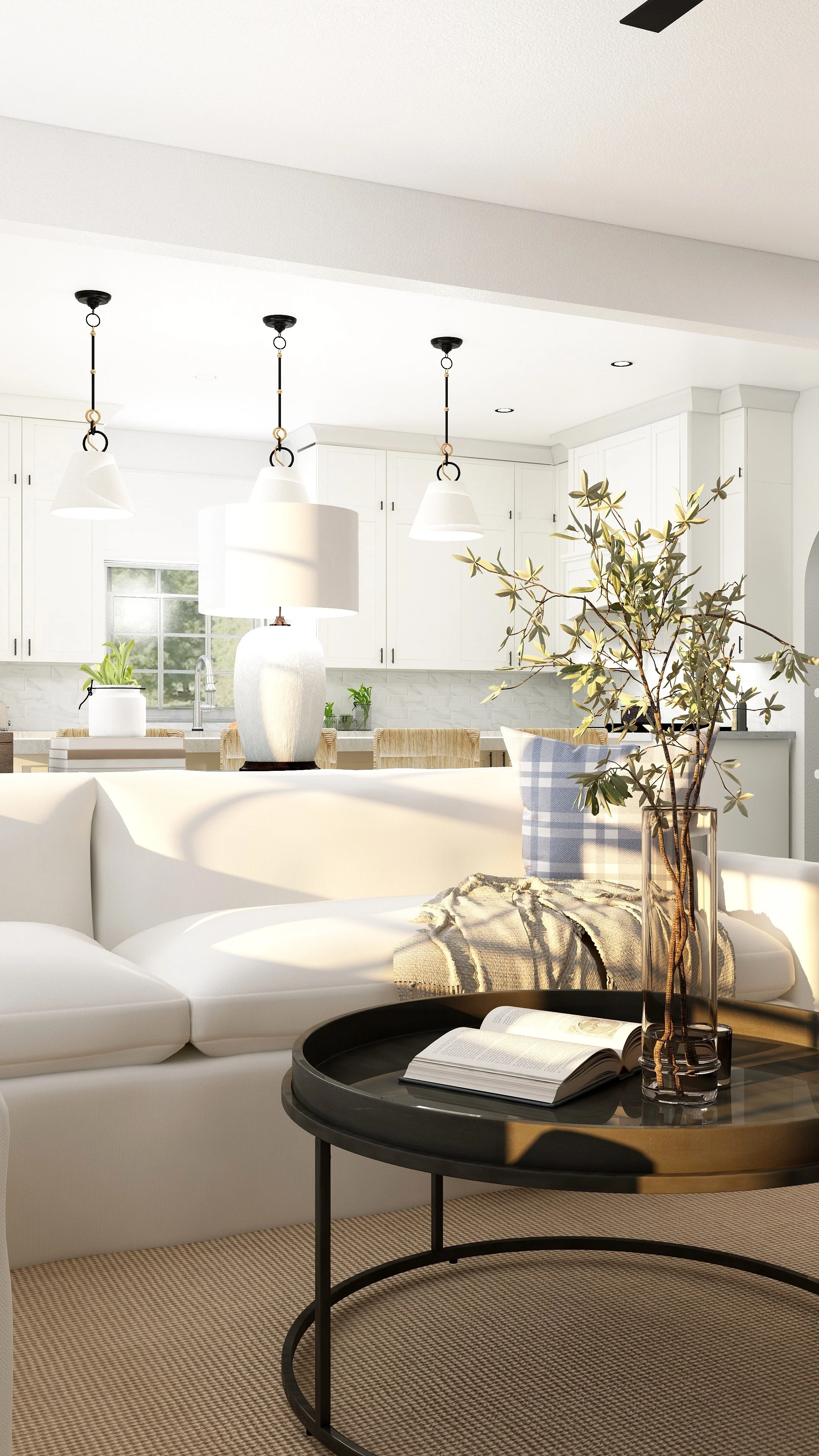 Living room with a white sofa, a round black coffee table with an open book and a vase with green branches, a beige carpet, and a view of a kitchen in the background with white cabinets and pendant lights.