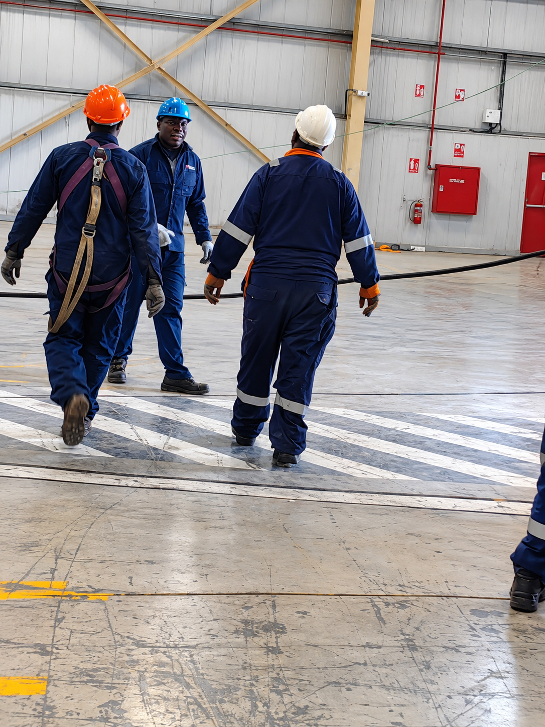 Workers in safety gear walking inside an industrial warehouse