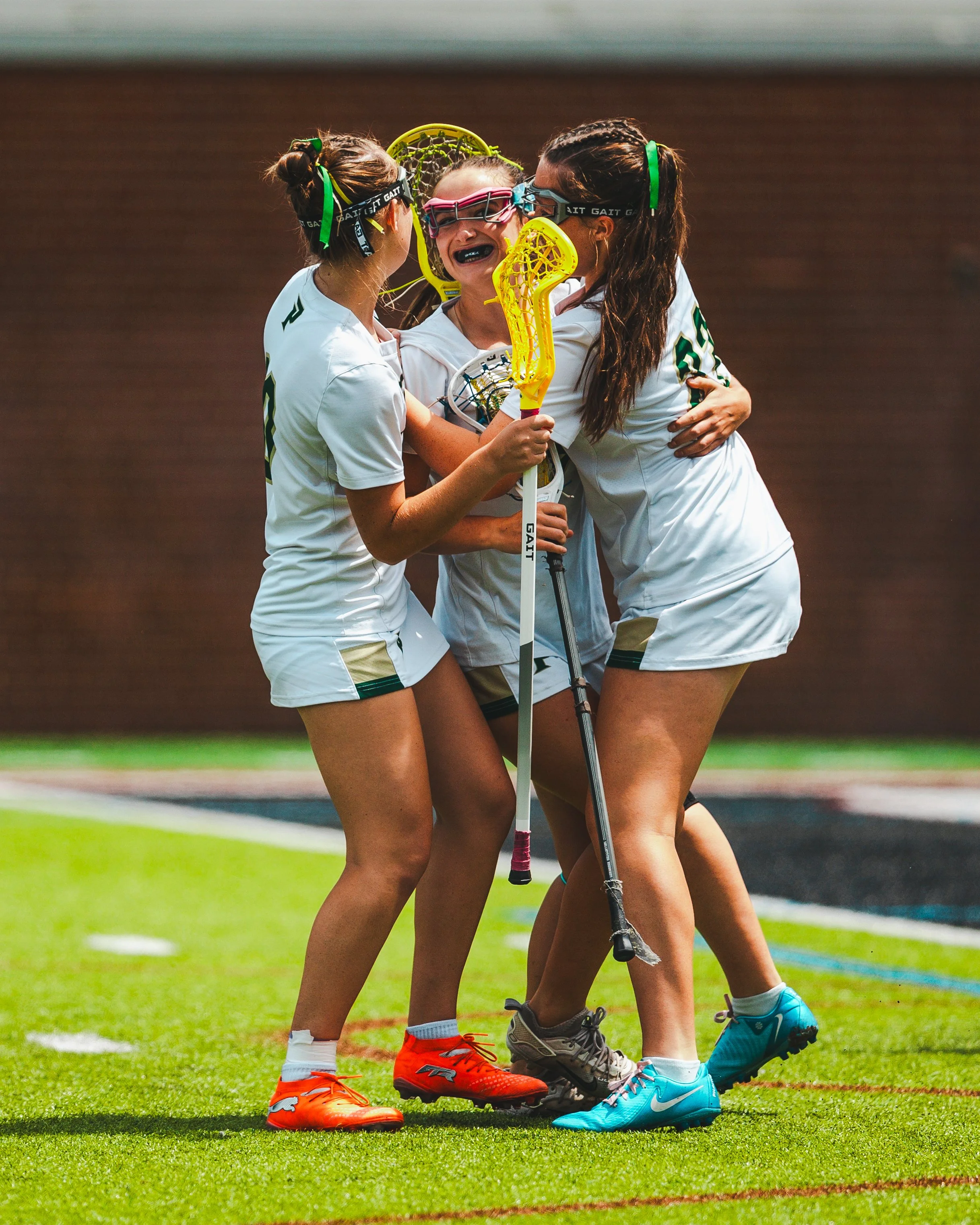 Lacrosse players hugging on a green field during a game.