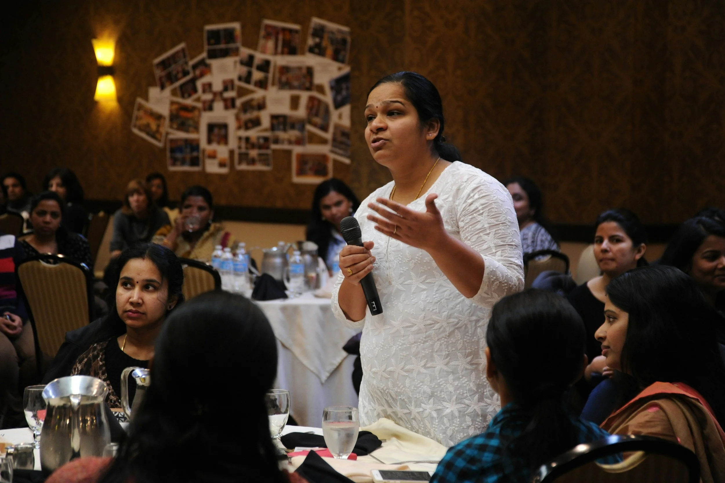 Woman speaking to a welcoming group of women at a community workshop
