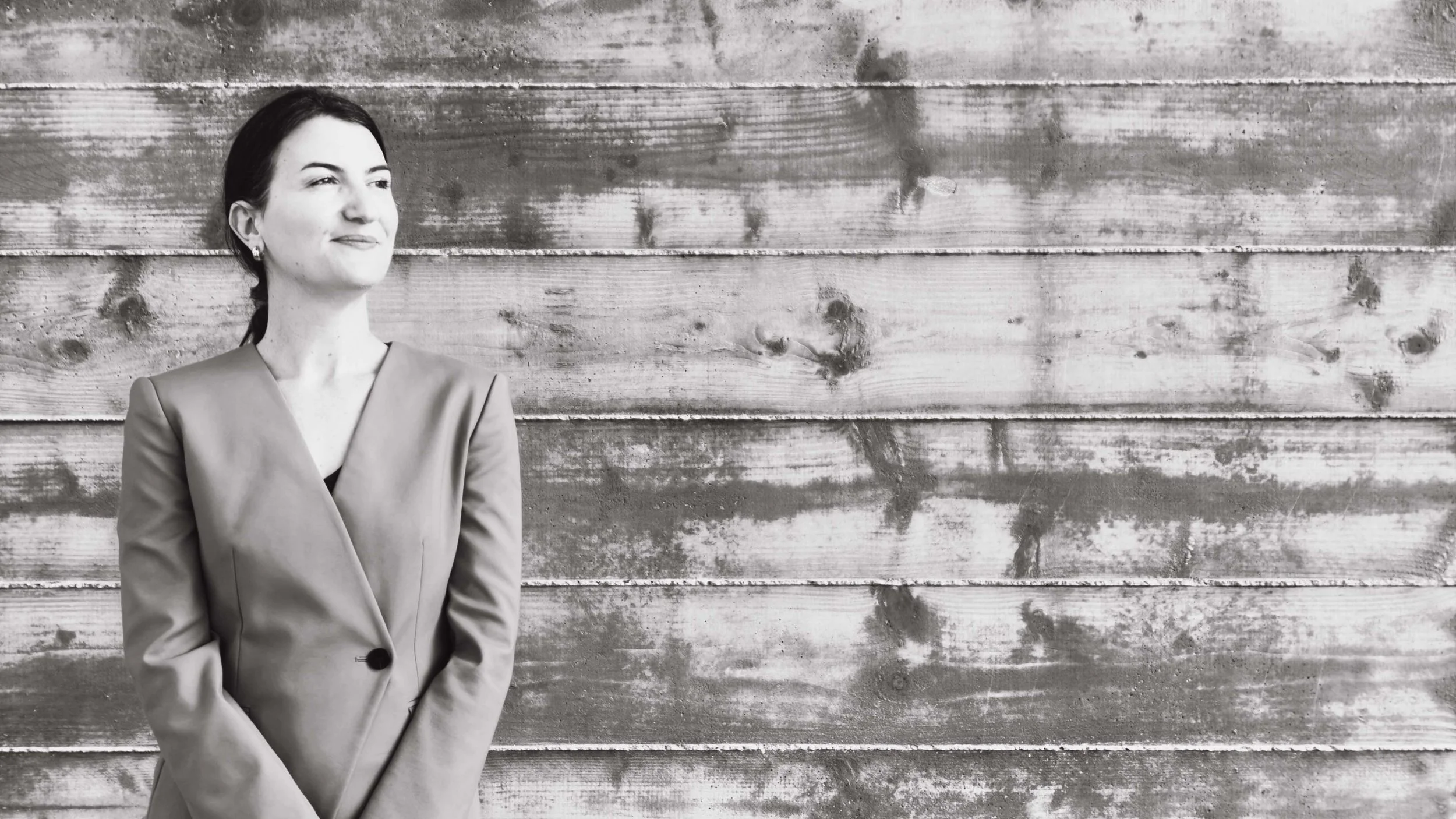 Black and white portrait of Maureen Brown, M&A advisor, in front of a weathered wood wall