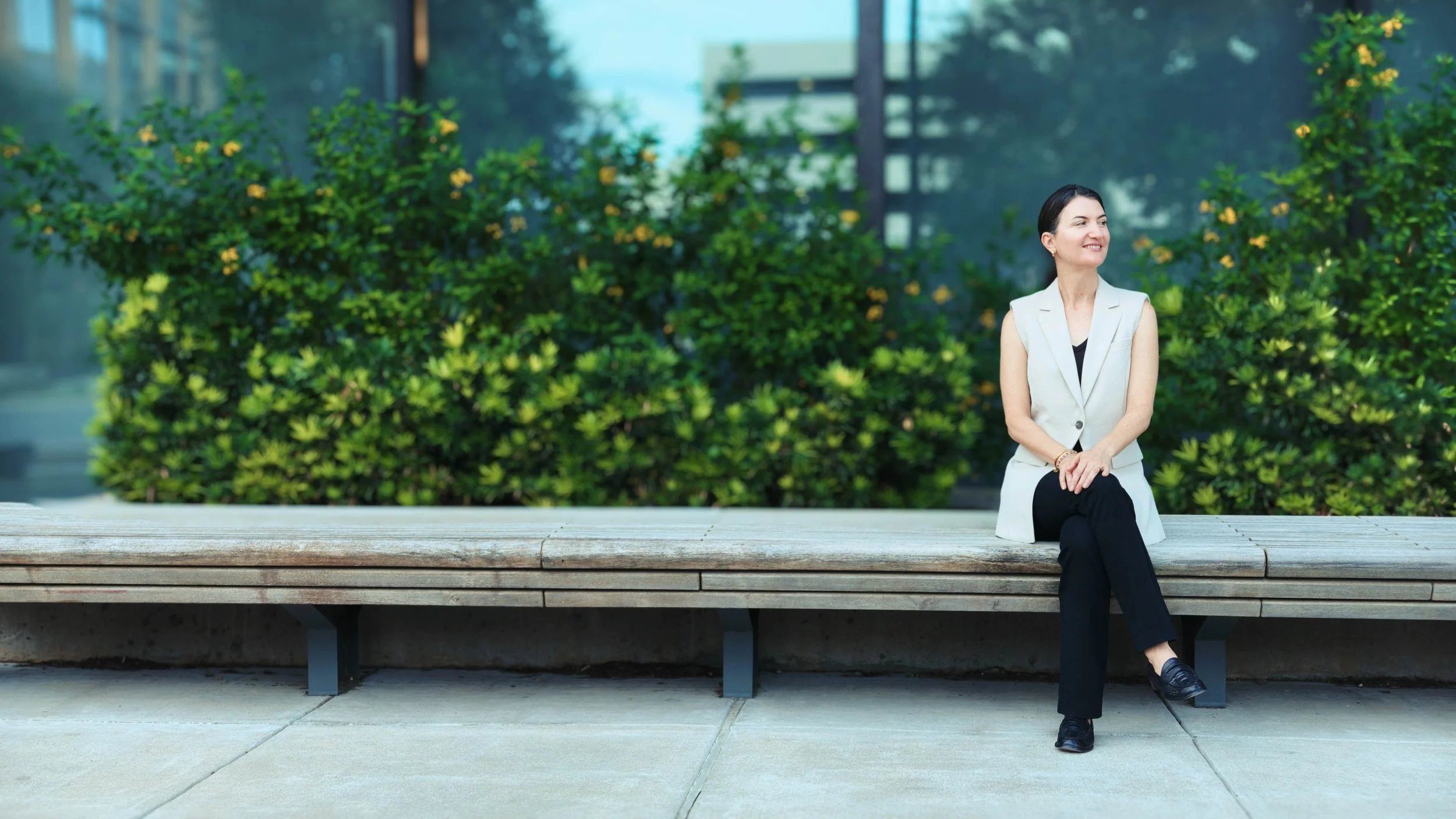 Maureen Brown, M&A advisor and founder of Exit with Mo, seated on a wooden bench outdoors in Austin