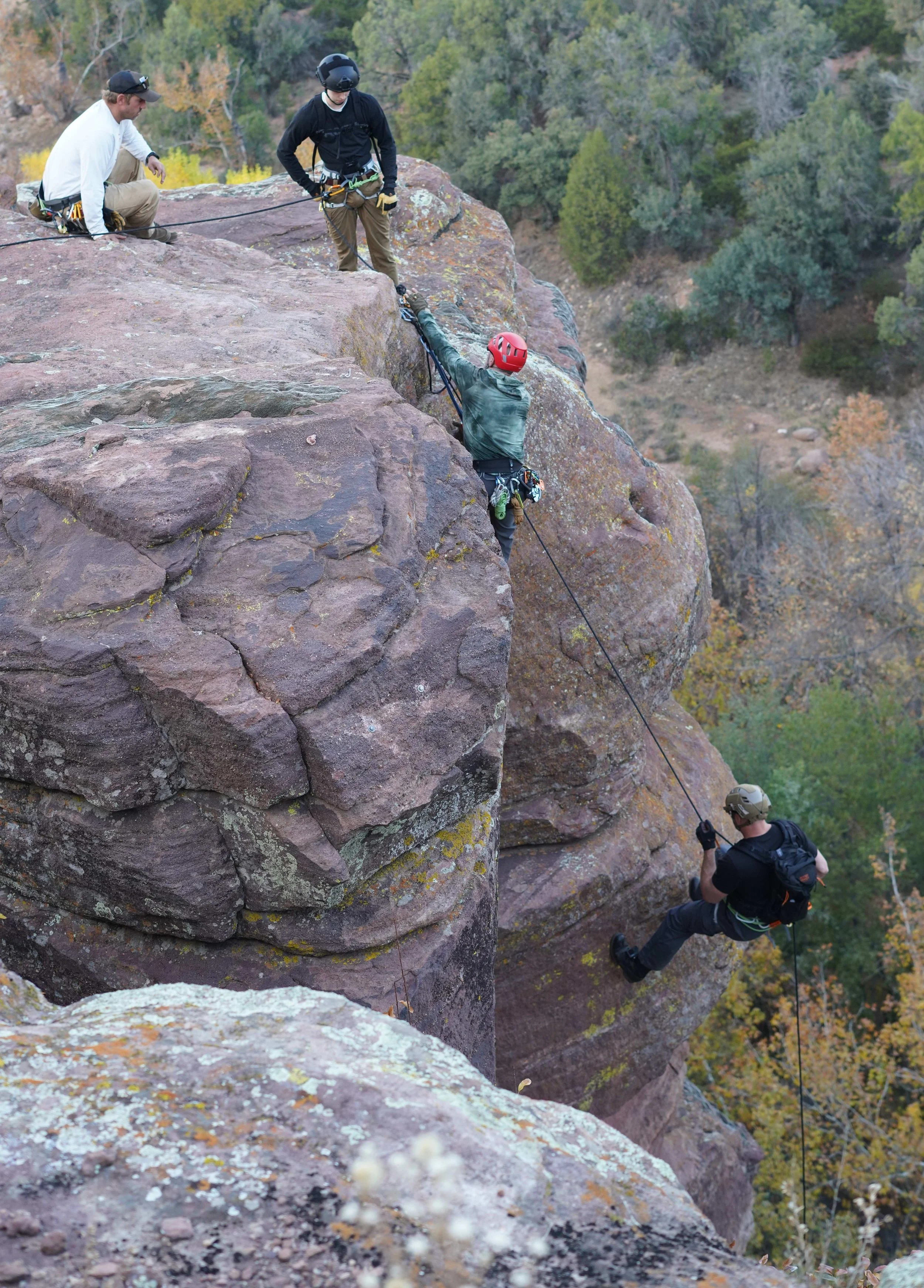 Participants work together through a technical rope challenge during a multi-day experiential leadership event designed to build trust, communication, resilience, adaptability, and teamwork under pressure.