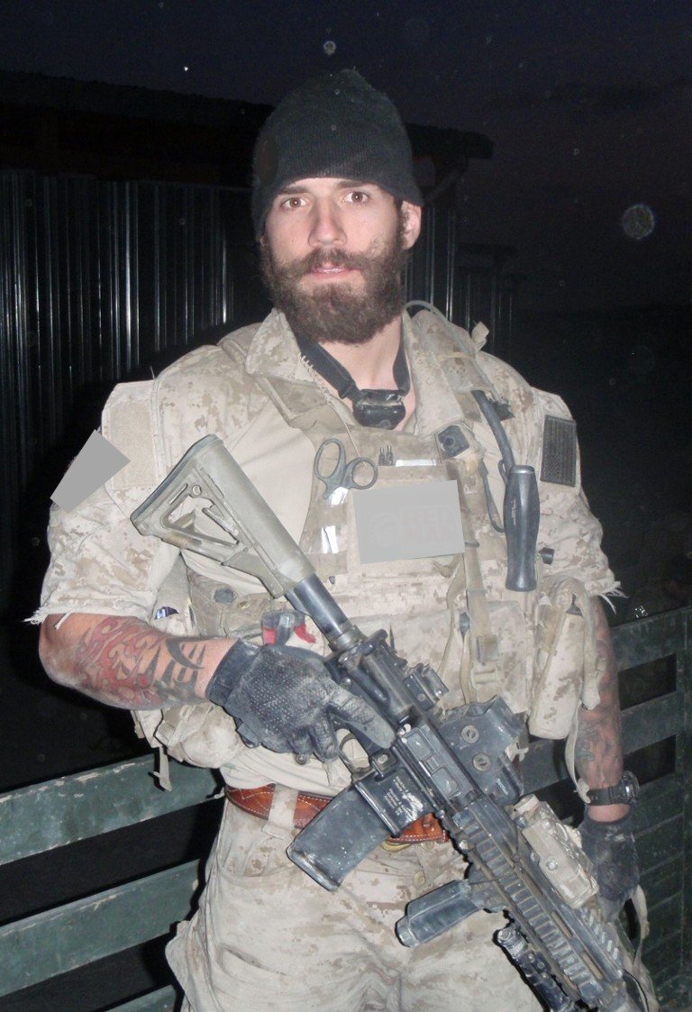A special operations operator dressed in desert camouflage gear holding a rifle during night time.