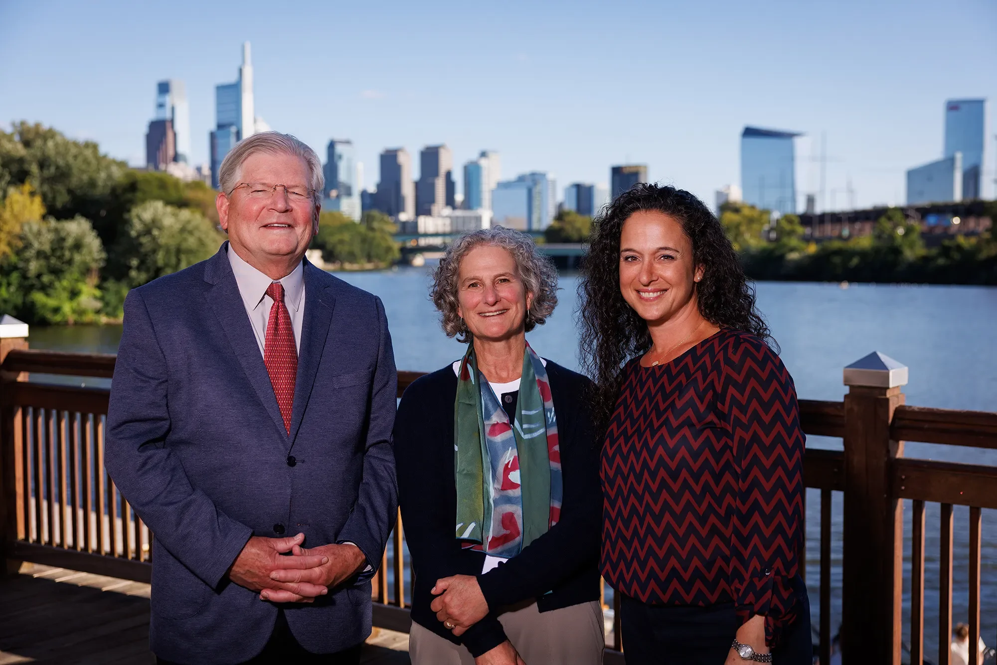 Jim, Amy, and Mariana standing on a deck in front of the Philadelphia skyline.