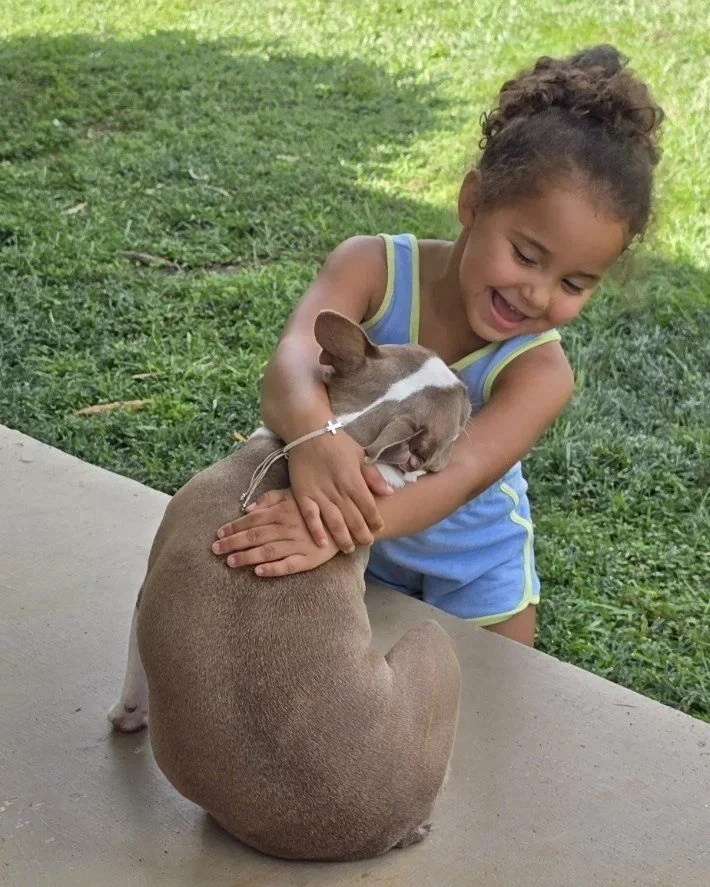 Young girl hugging a dog outdoors at Nine Acres.