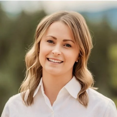 A young woman with blonde hair smiling outdoors.