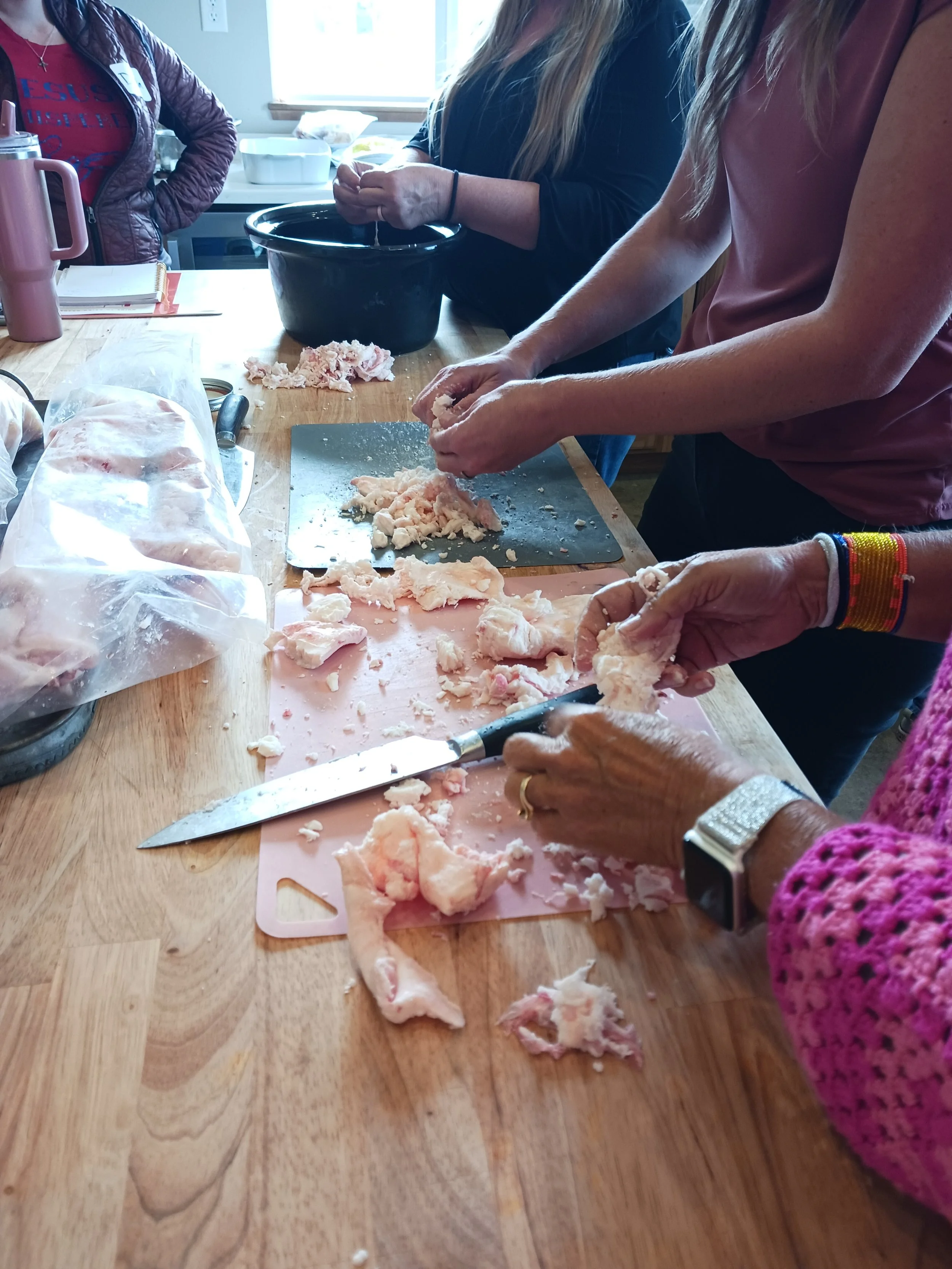 Women rendering fats in class together.